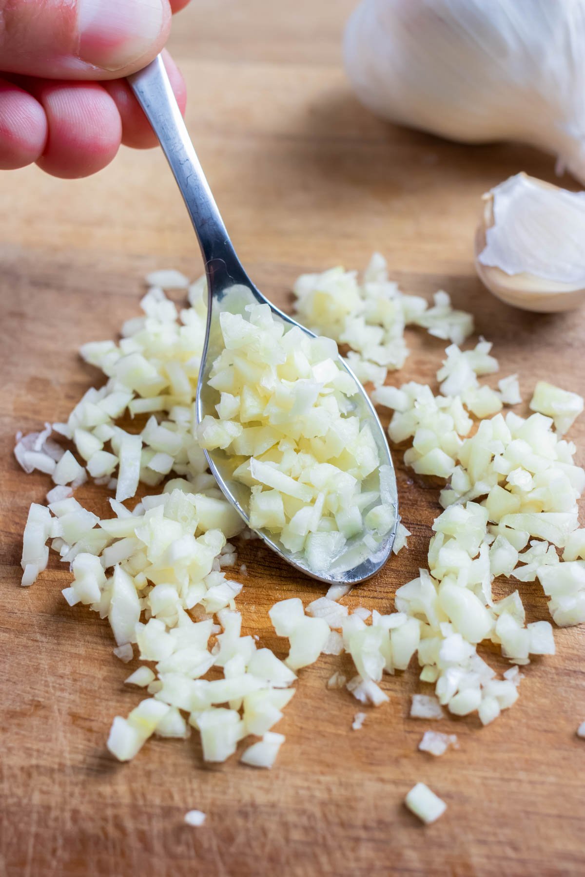 A spoon is used to hold the mince garlic for recipes.