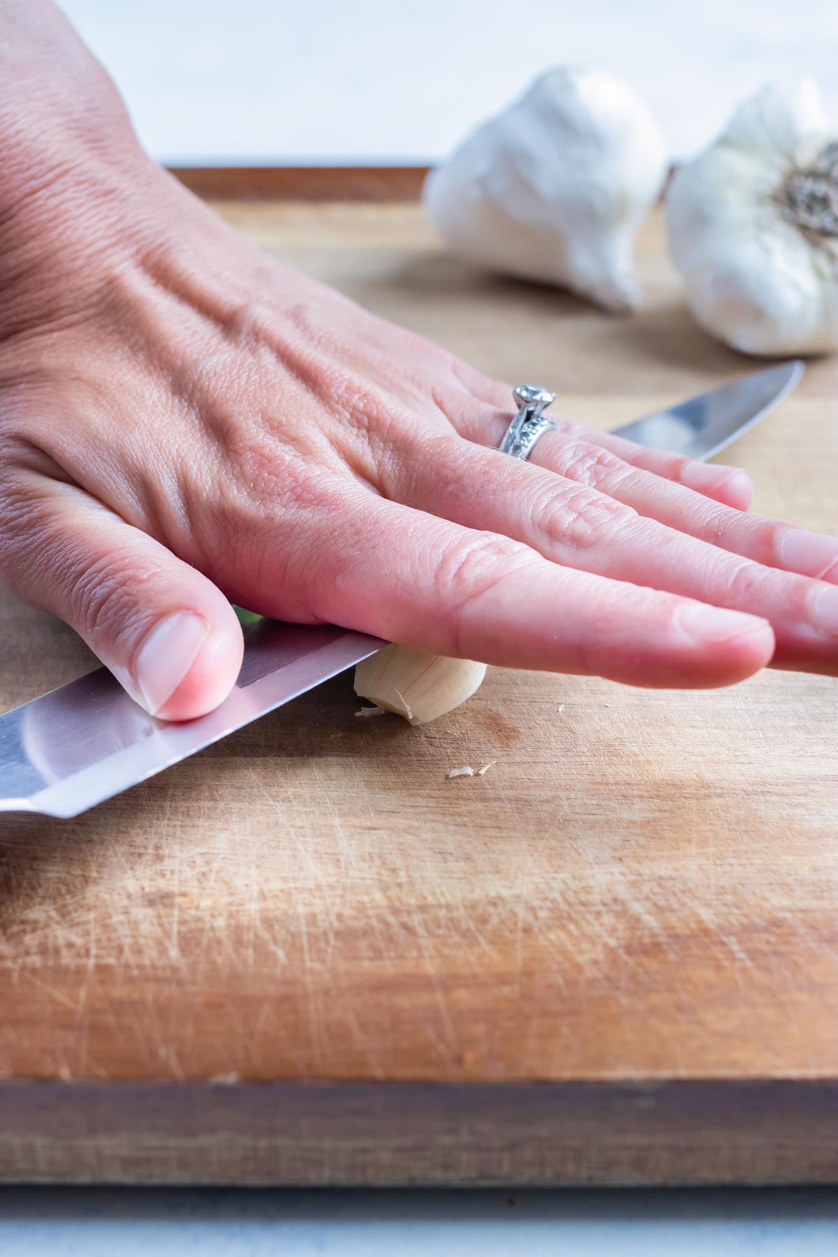 Pressure is applied to the garlic clove with a knife.