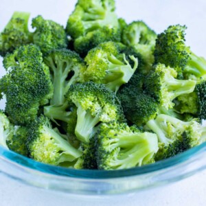 Steamed broccoli is in a clear bowl.