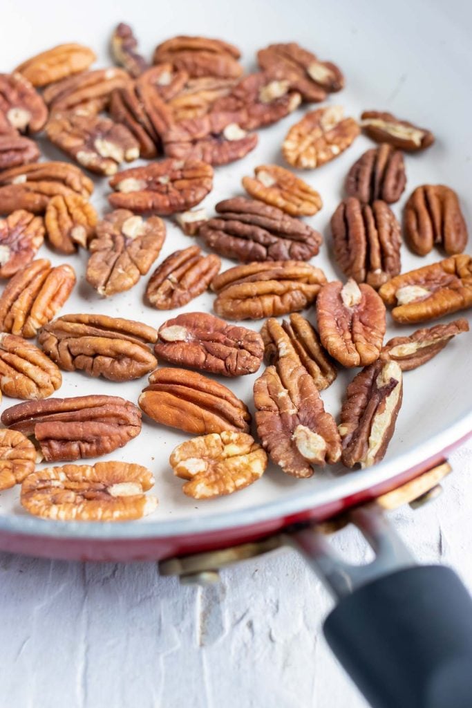 Pecan halves are being toasted in a pan.