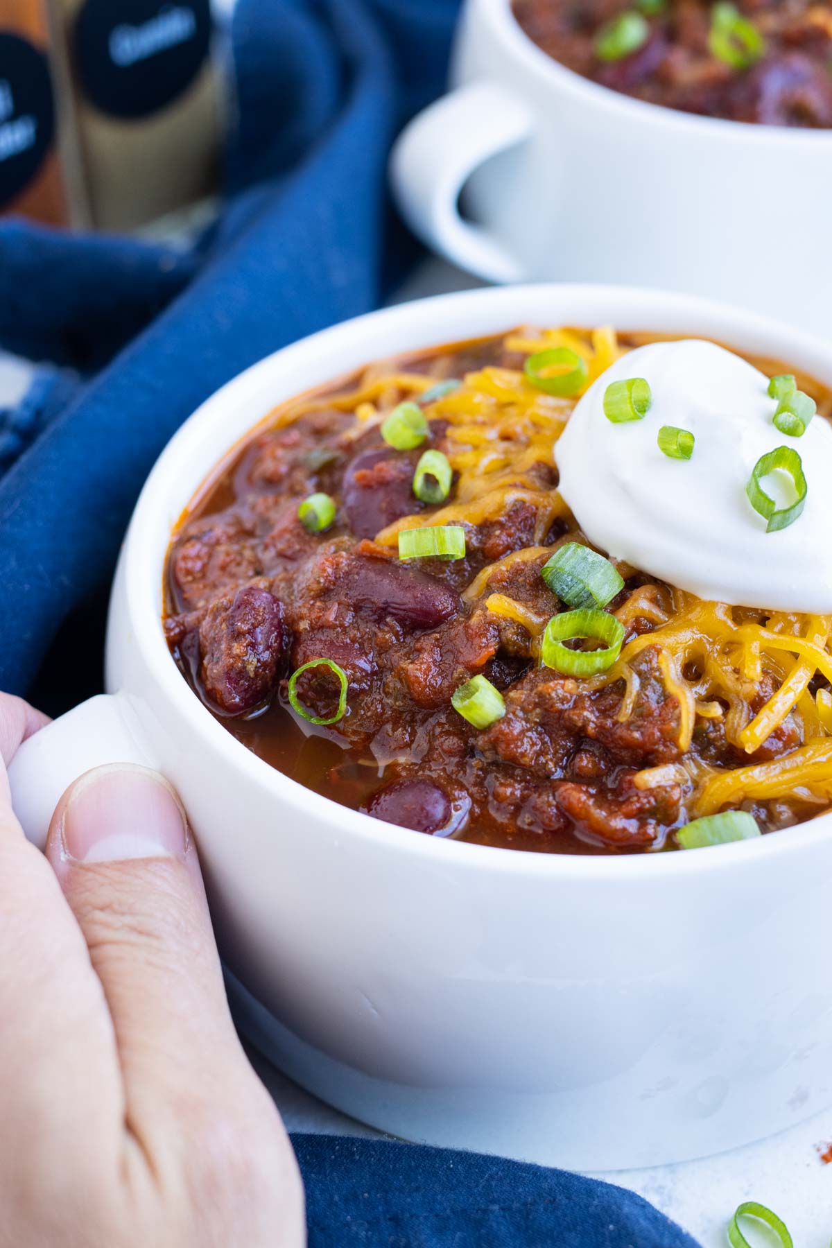 Instant Pot Chili in a white soup bowl with sour cream and cheese on top.