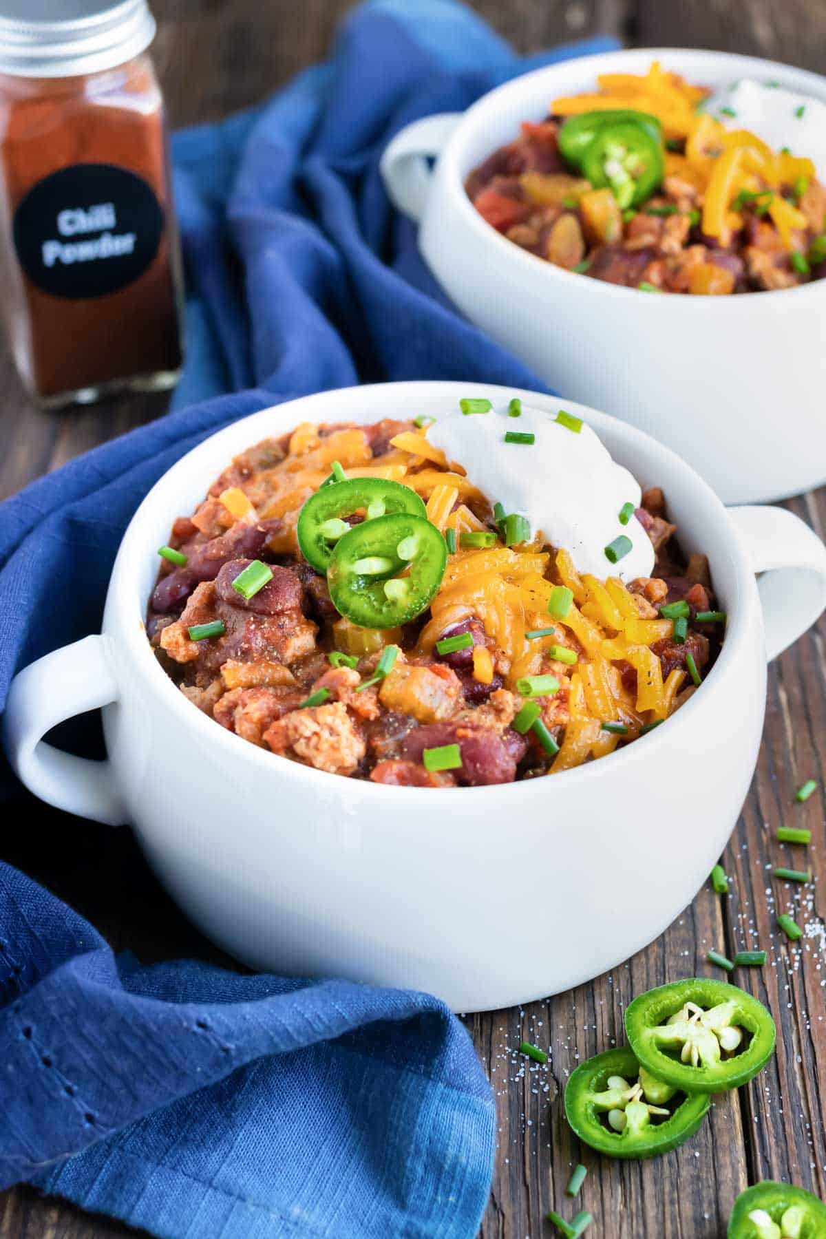 A bowl of Instant Pot turkey chili topped with sour cream and shredded cheddar cheese.