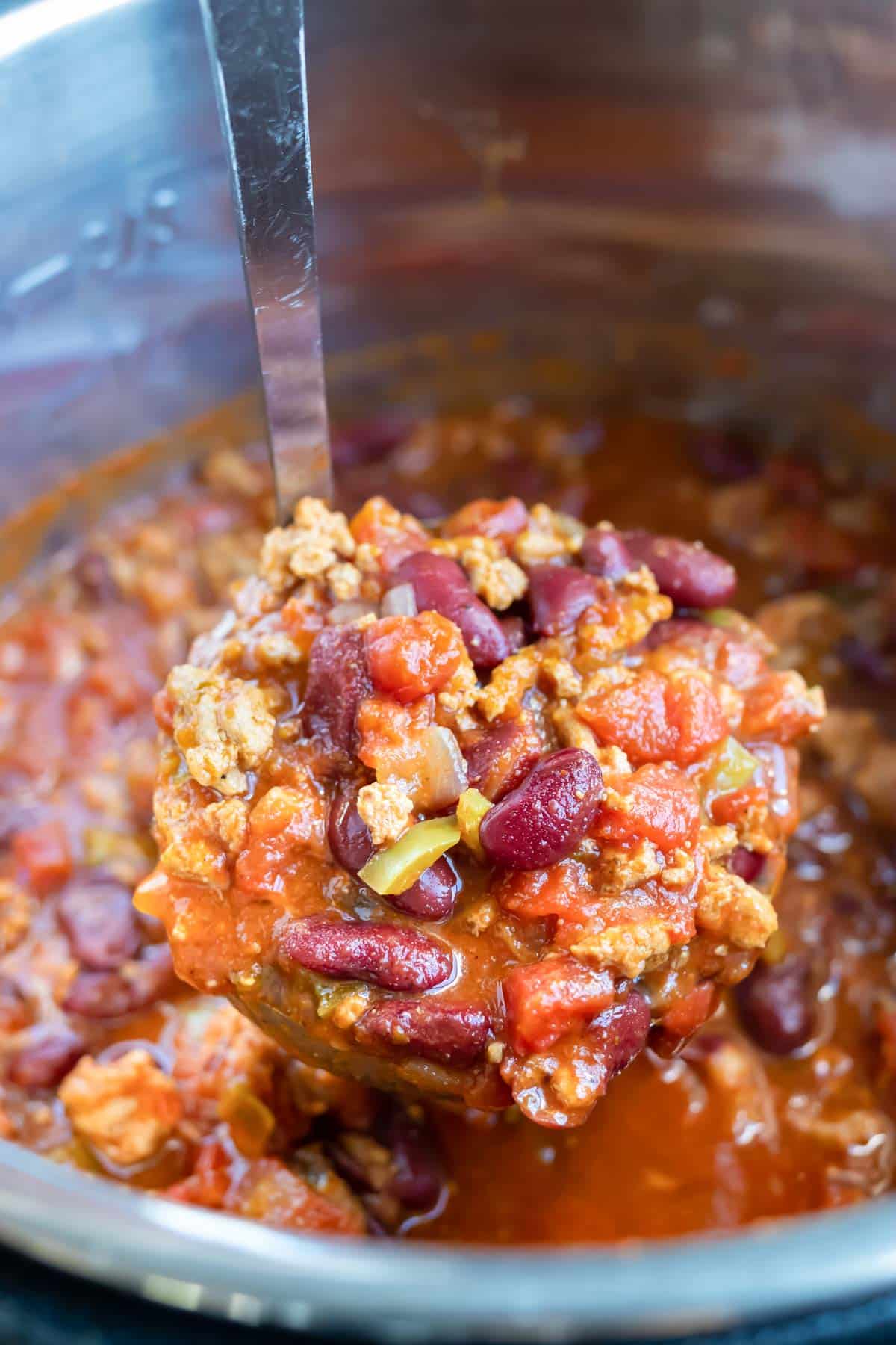 A ladle scooping out a serving of ground turkey chili from an Instant Pot.