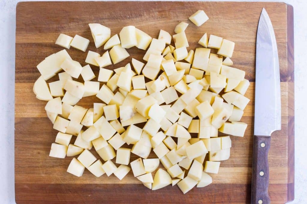Peeled and cubed Russet potatoes on a cutting board.
