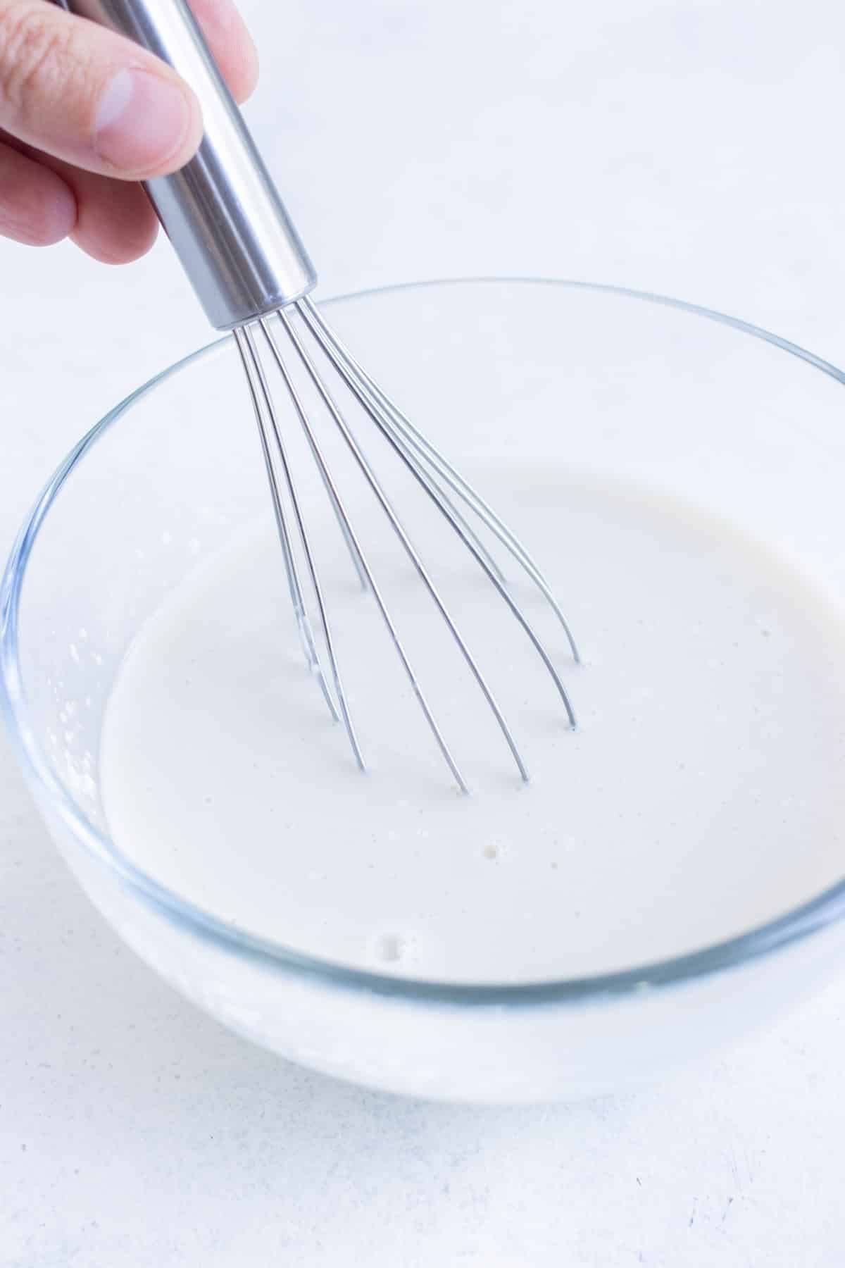 A whisk stirs a cornstarch slurry.