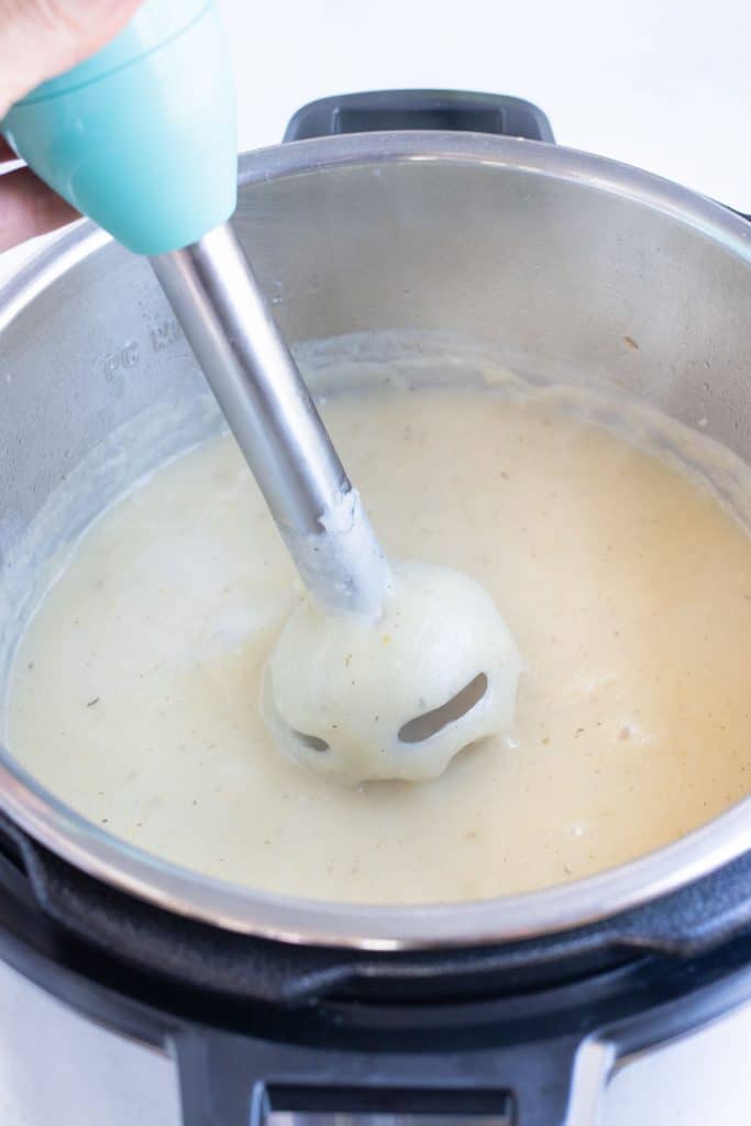 An immersion blender puréeing creamy potato soup without heavy cream.