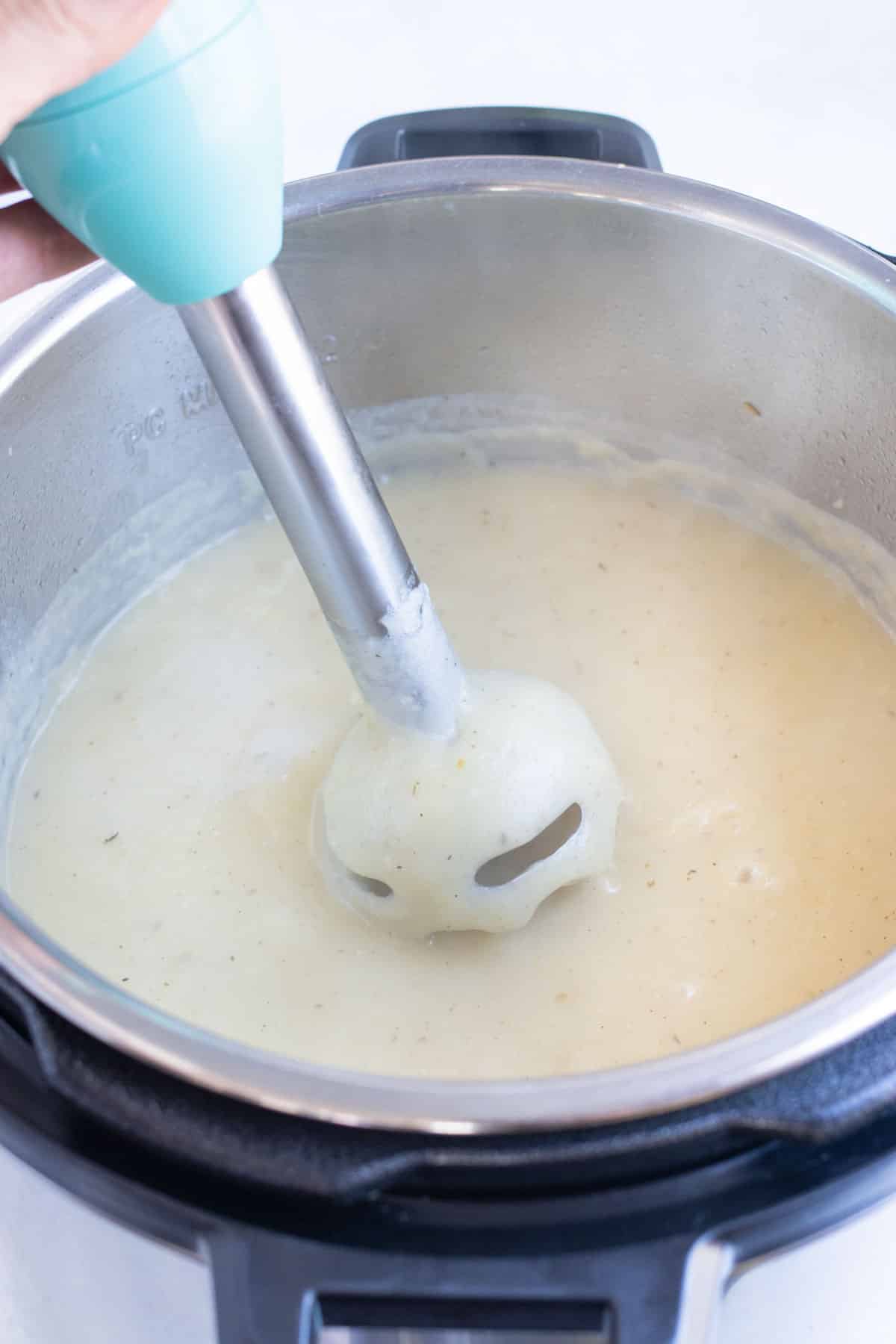 An immersion blender purees potato soup.