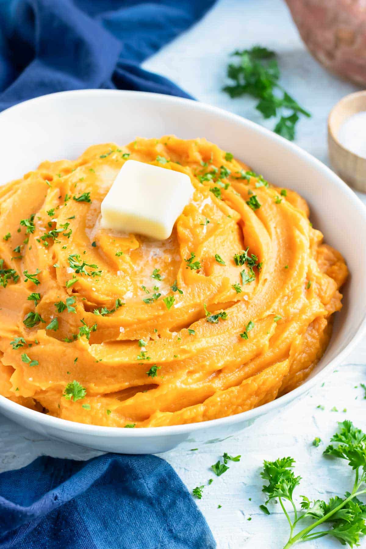 A bowl full of creamy mashed sweet potatoes that are savory with garlic and herbs.