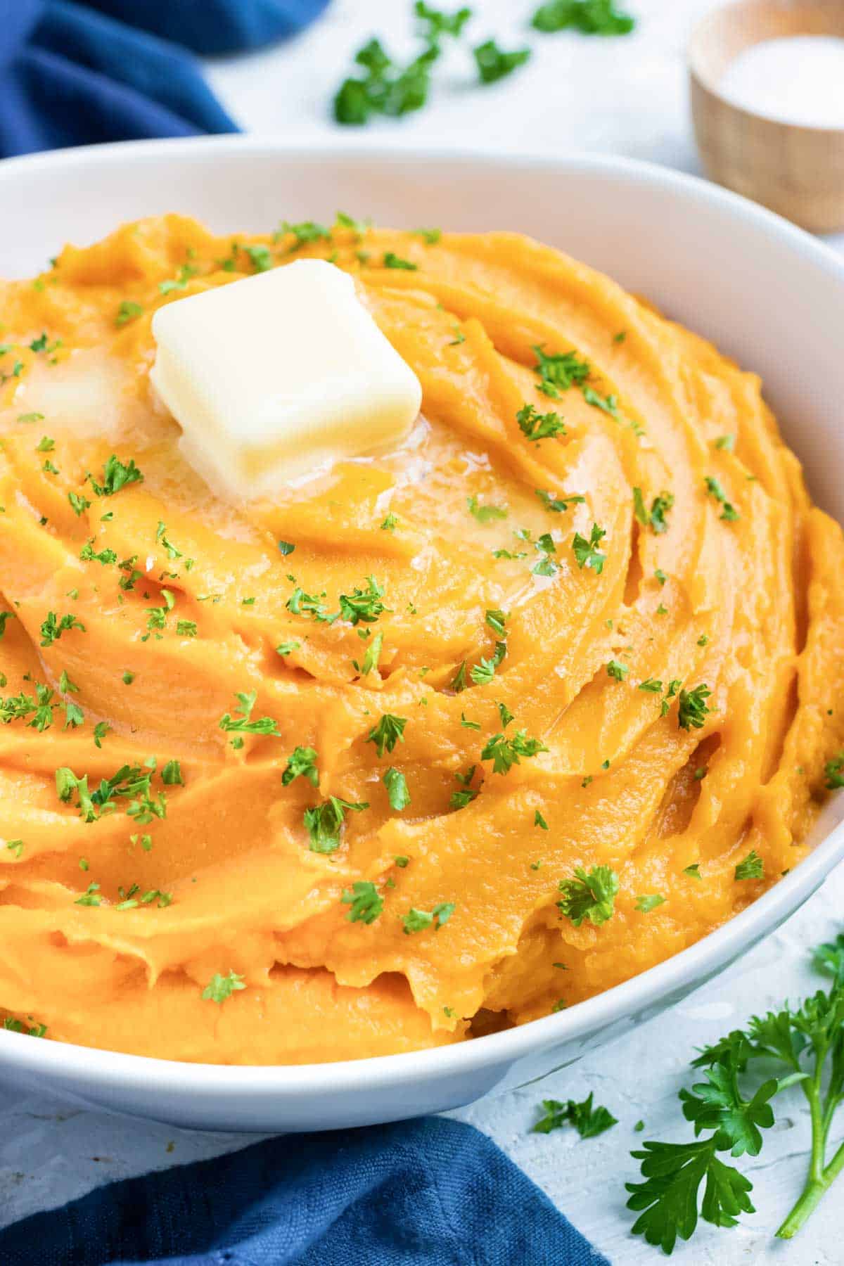 Easy mashed sweet potatoes in a white serving bowl with butter.