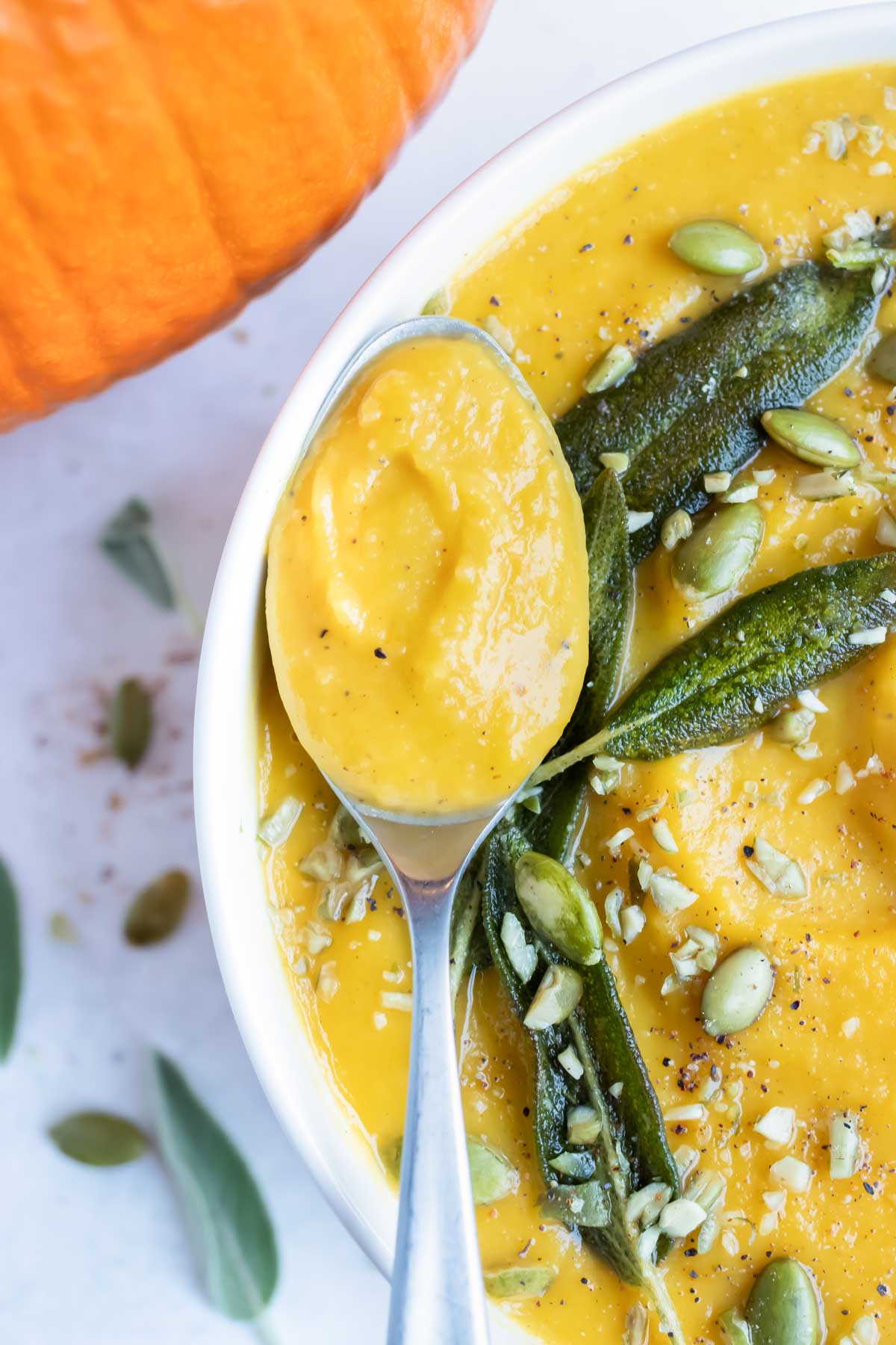 A spoon is holding this gluten-free and dairy-free pumpkin soup recipe.