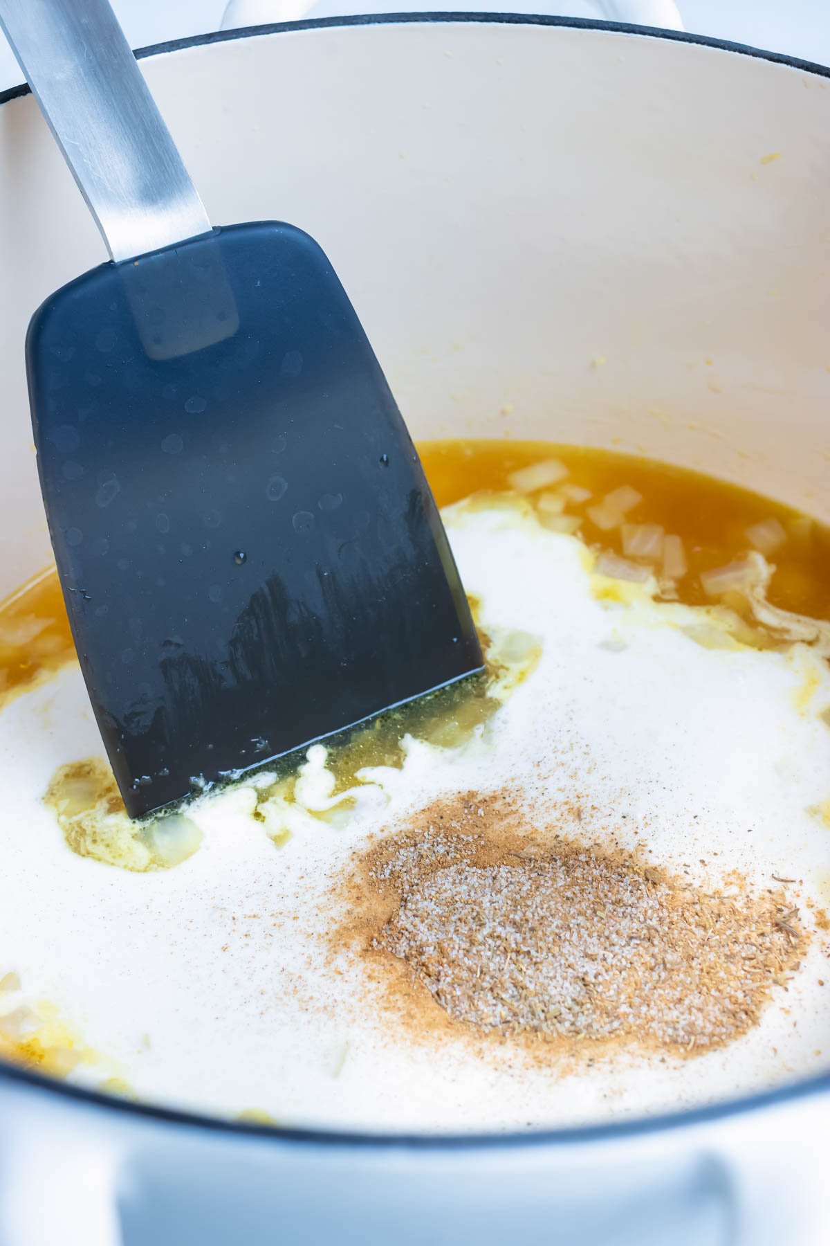 Sage, thyme, cinnamon, nutmeg, salt, and pepper are stirred into the broth mixture.