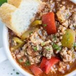 A bowl of soup is shown loaded with ground beef, bell peppers, and rice.