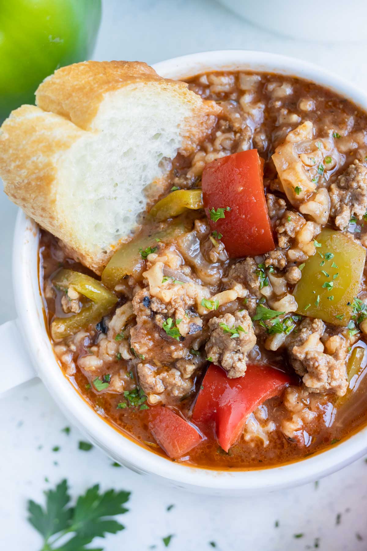 A bowl of soup is shown loaded with ground beef, bell peppers, and rice.