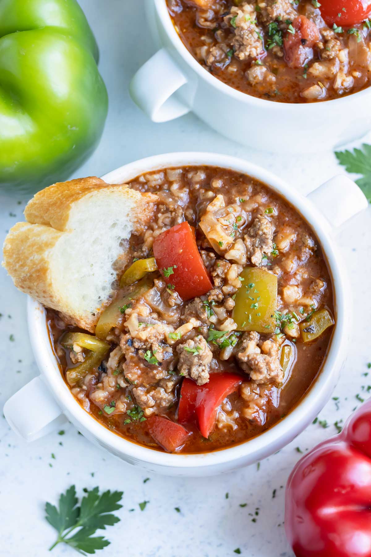 Close up of one pot stuffed pepper soup served with a slice of toasted baguette.