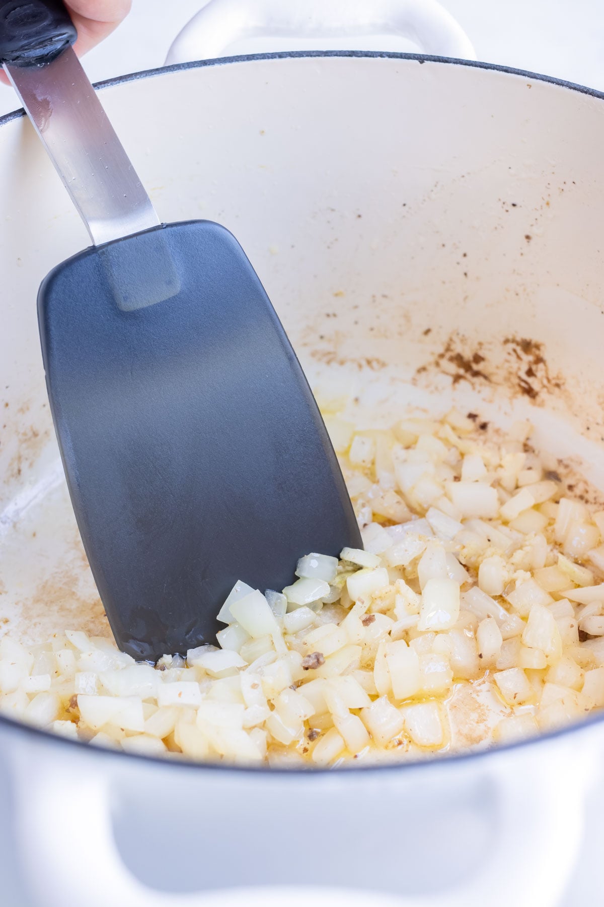 Diced sweet onion softening in a Dutch oven for easy stuffed pepper soup.