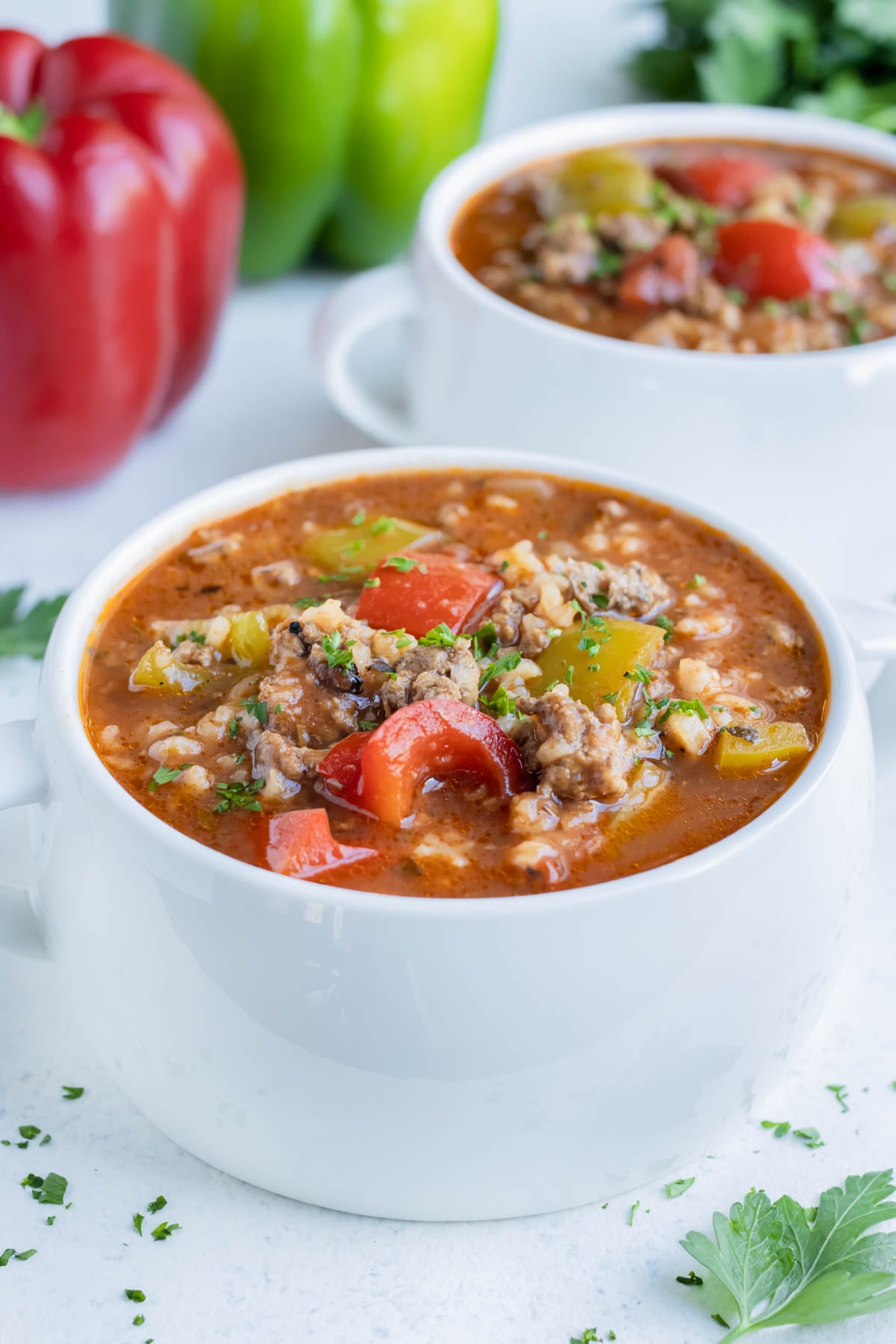 Overhead bowl of stuffed pepper soup with ground beef, rice, and red and green bell peppers.