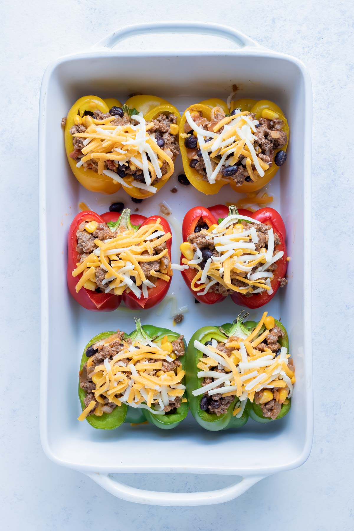 Six rows of stuffed bell peppers are baked for a healthy dinner.
