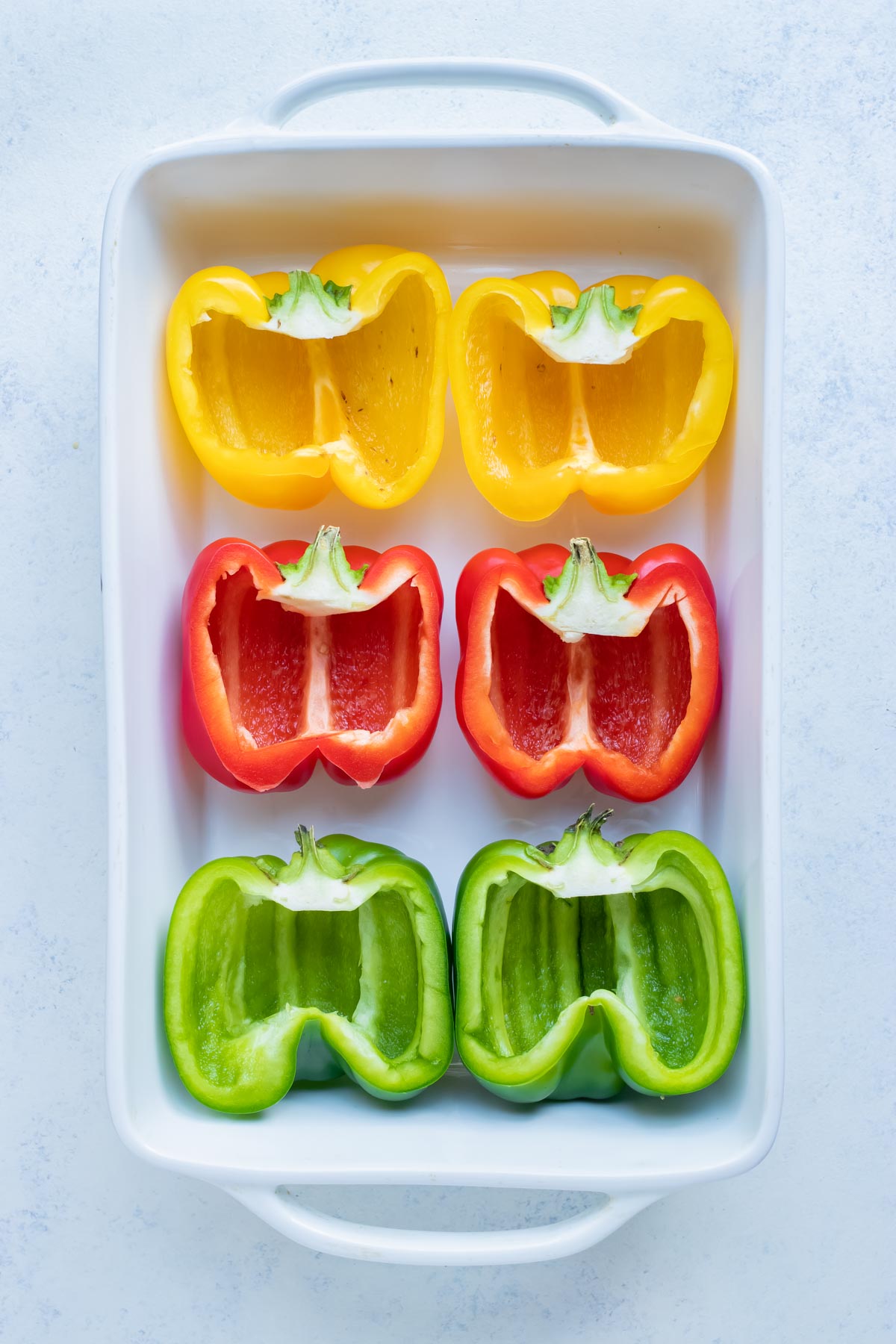 The bell peppers are lined in a baking dish before filling.