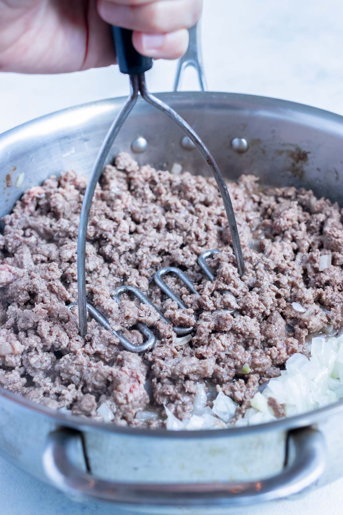 The ground meat is added to the sautéed onions.