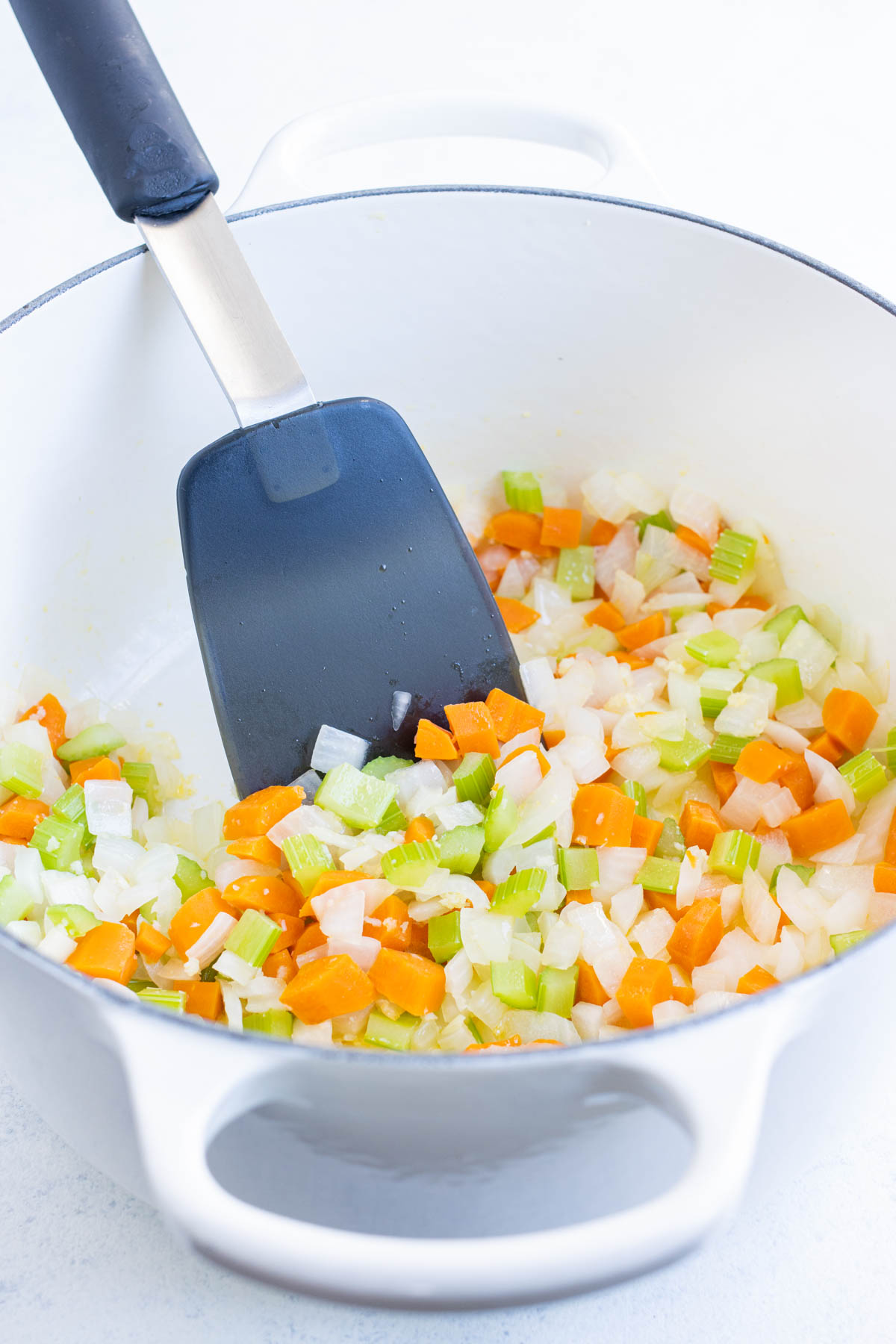 Carrots, onion, and celery are sauteed in a Dutch oven.