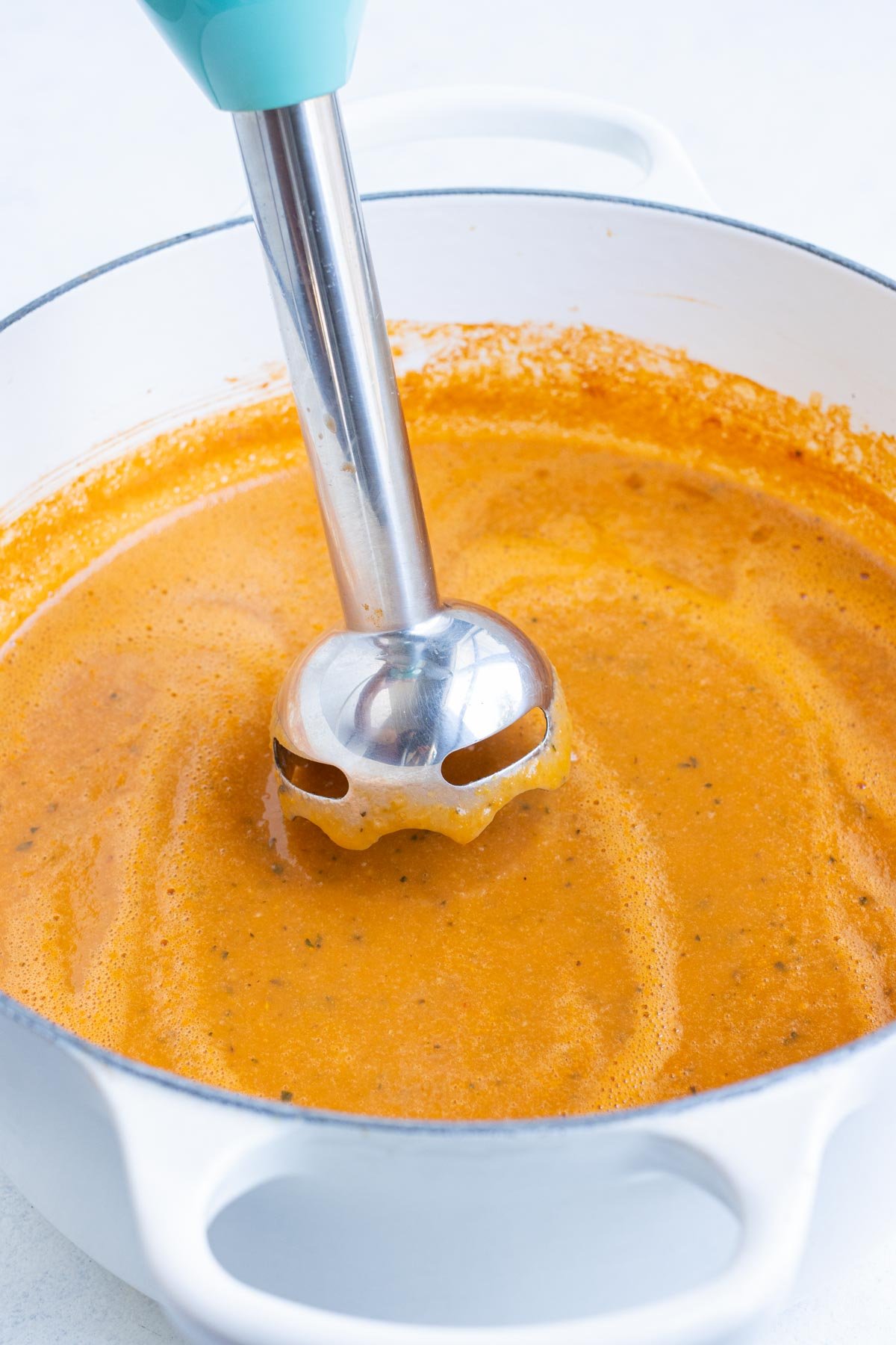 An immersion blender purees the tomato bisque.