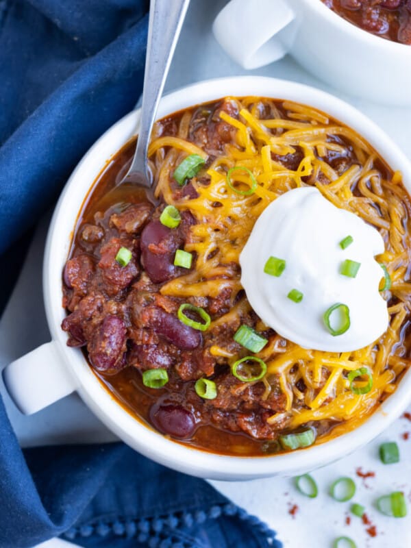 An overhead shot of chili topped with cheese and sour cream.