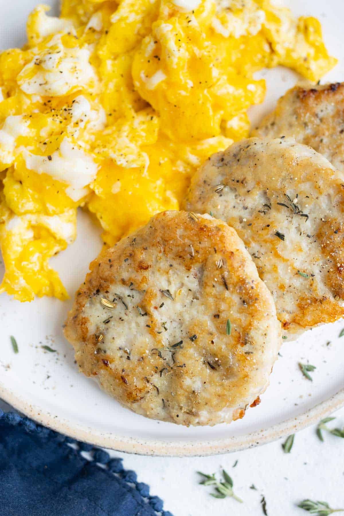 A closeup of chicken sausage and eggs on a white plate.