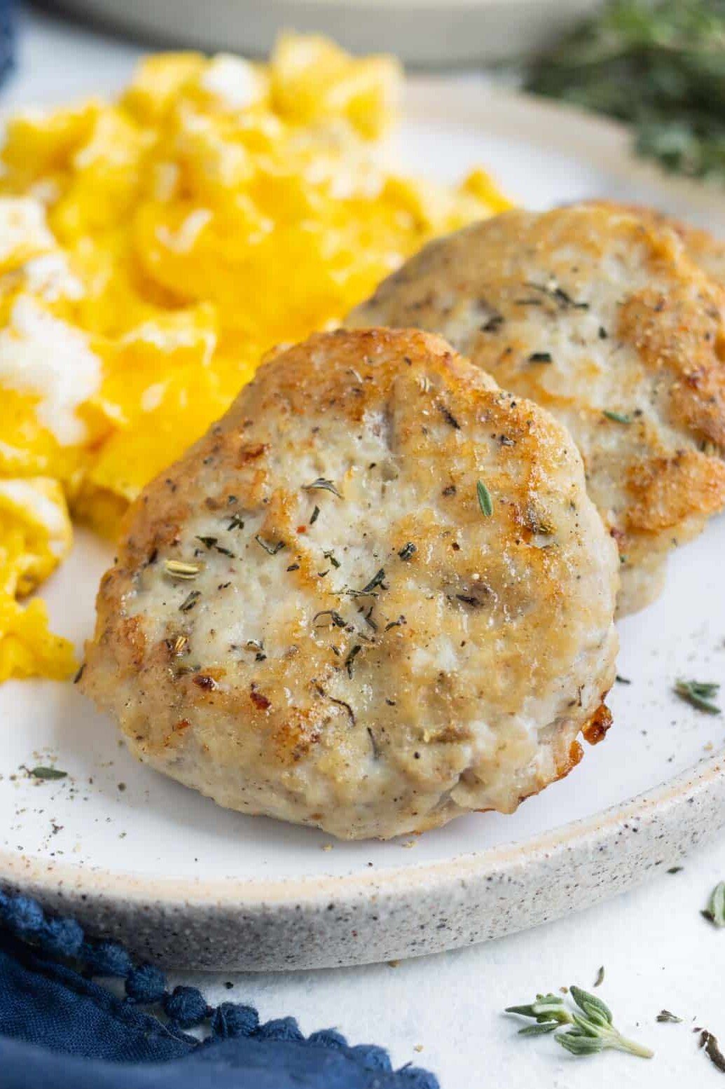 Homemade Chicken Breakfast Sausage Patties RECIPE served on a white plate and with scrambled eggs.