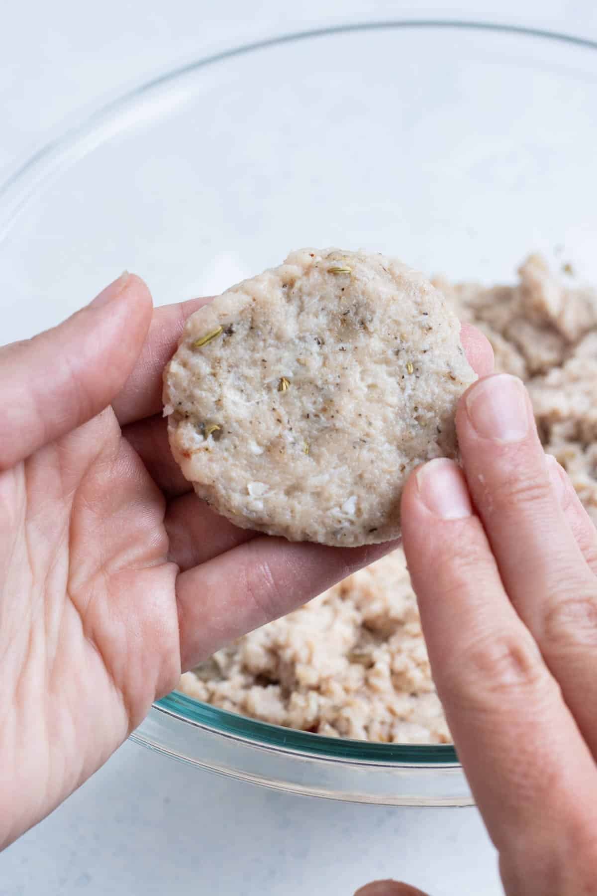 Sausage patties are formed and pressed in a hand.
