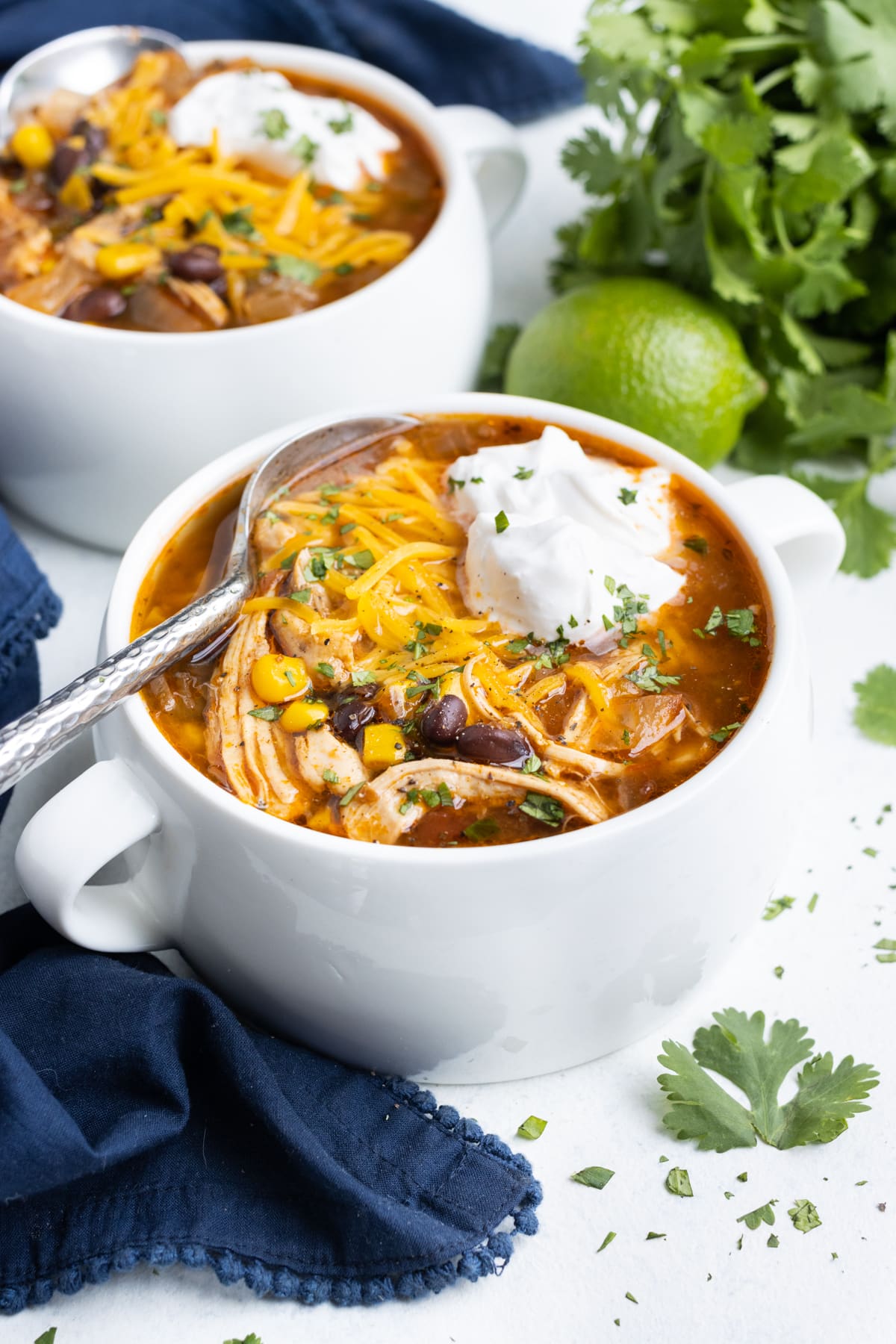 Two bowls of chicken taco soup are loaded with sour cream and cheese.
