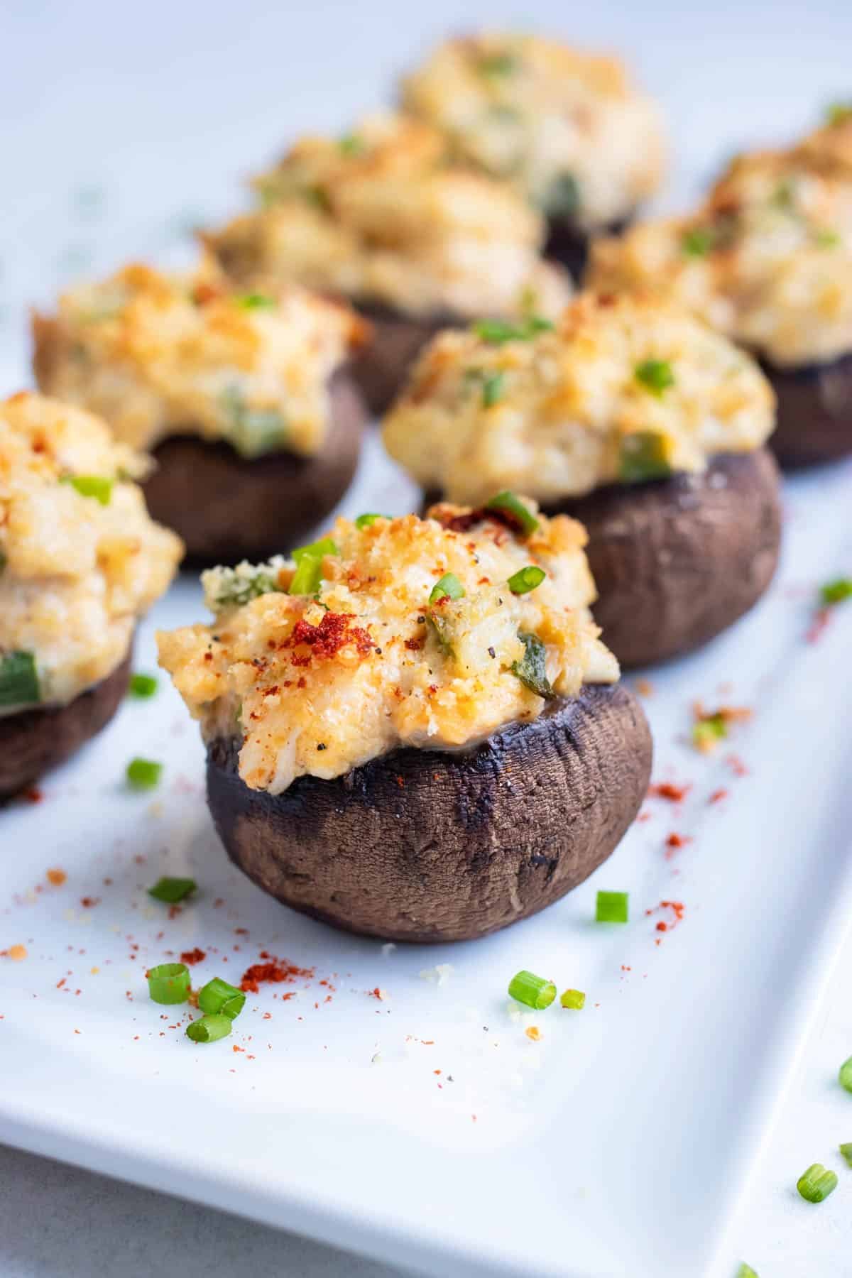 Creamy crab stuffed mushrooms are served on a white tray.