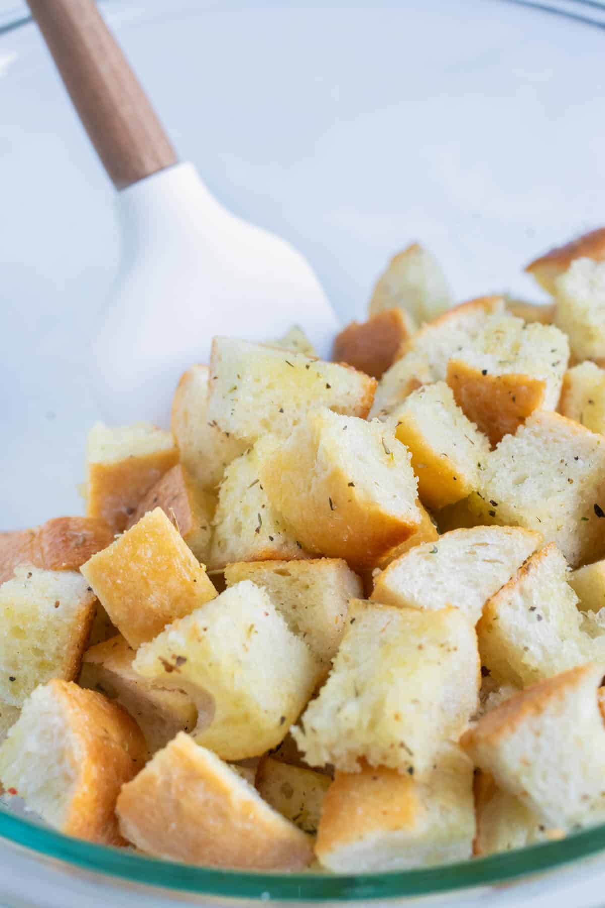 Bread cubes are mixed with oil and seasonings.