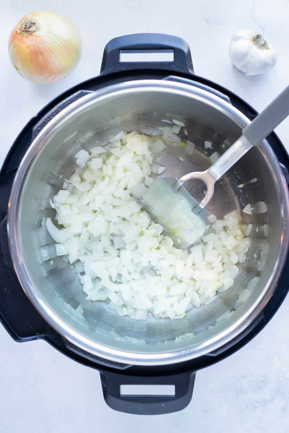 Diced onions are sautéed in the pressure cooker.
