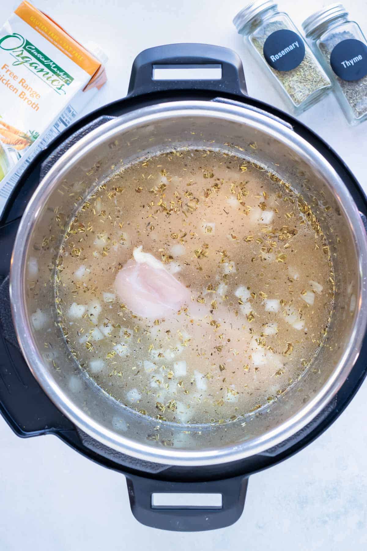 Broth, sautéed vegetables, and chicken breast are cooked in the instant pot.