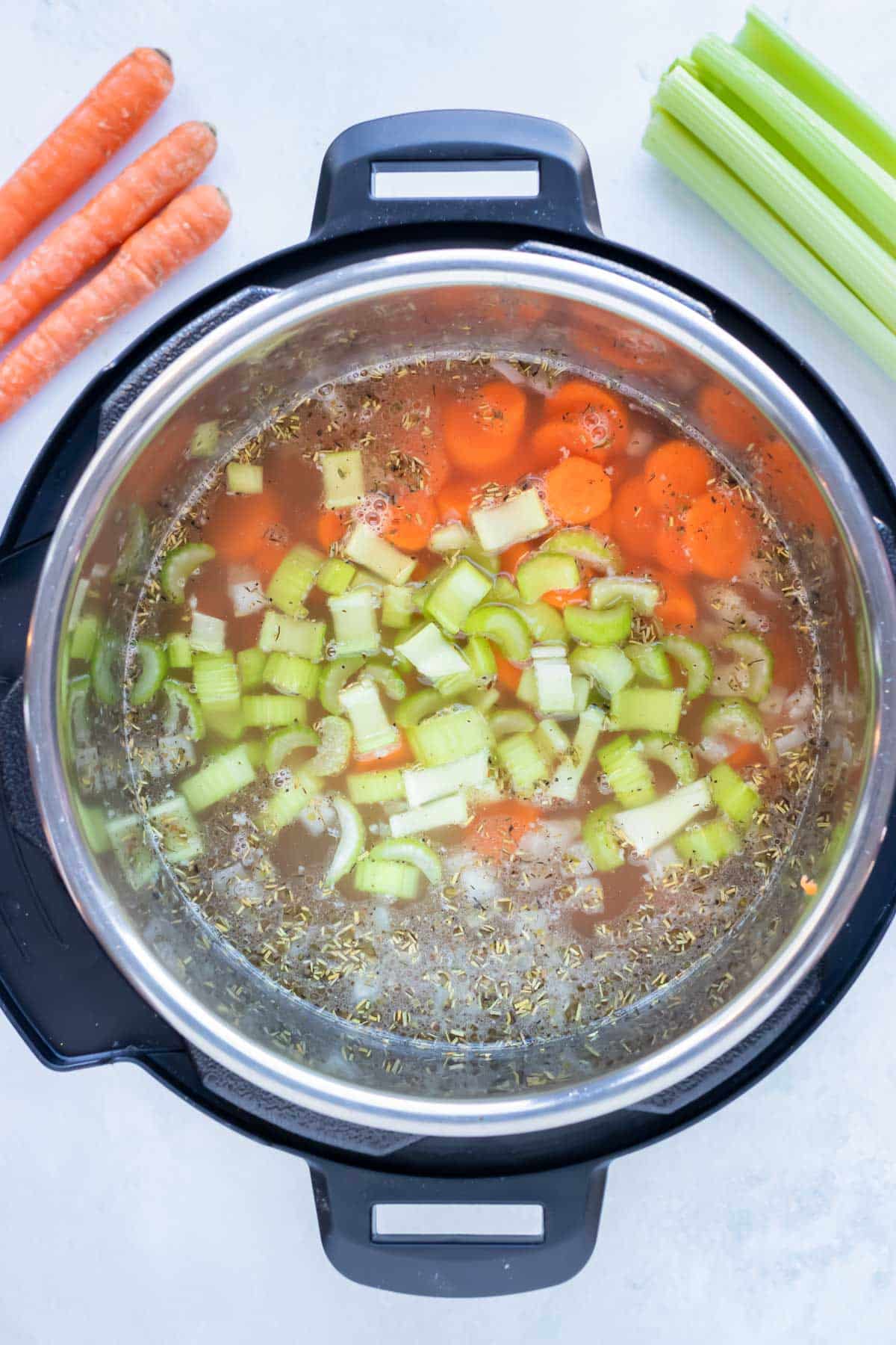 Chopped carrots, celery, and broth are cooked in the instant pot.