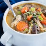 Easy pressure cooker soup is served with a spoon in a white bowl.