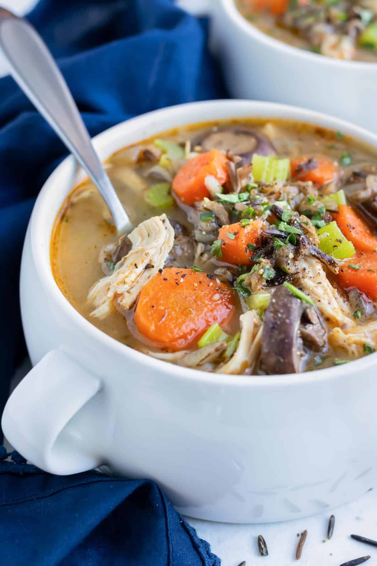 Easy pressure cooker soup is served with a spoon in a white bowl.