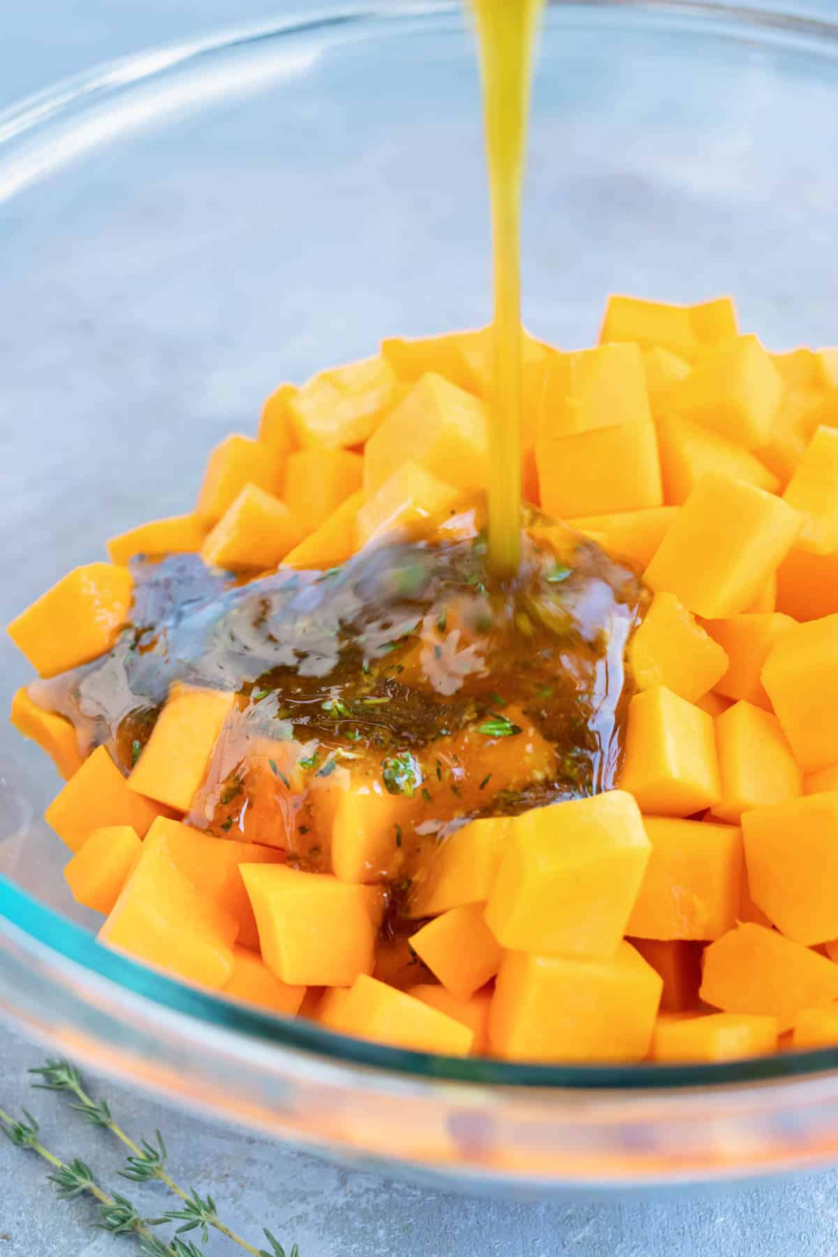 An herb sauce is poured over butternut squash in a bowl.