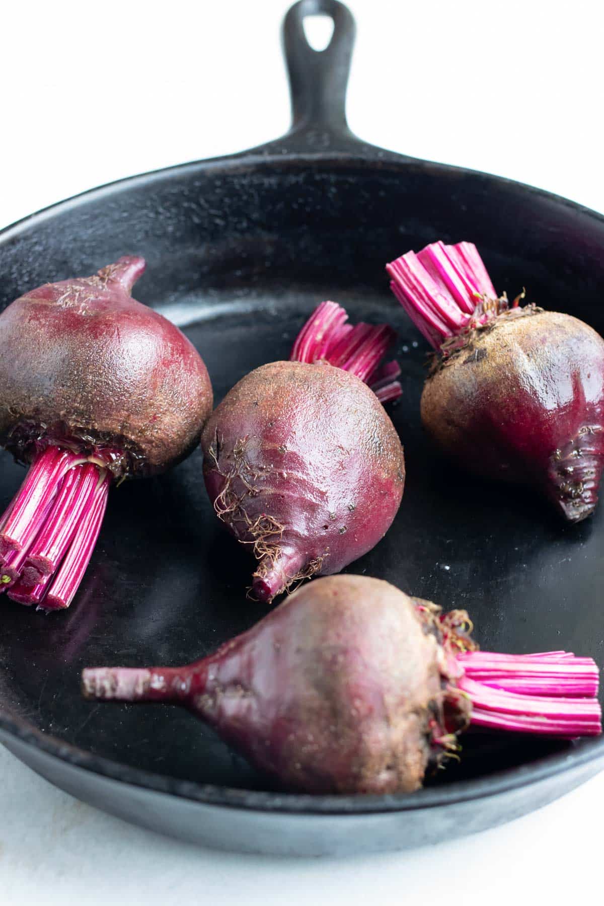 Beets are added to a cast iron skillet and baked in the oven.