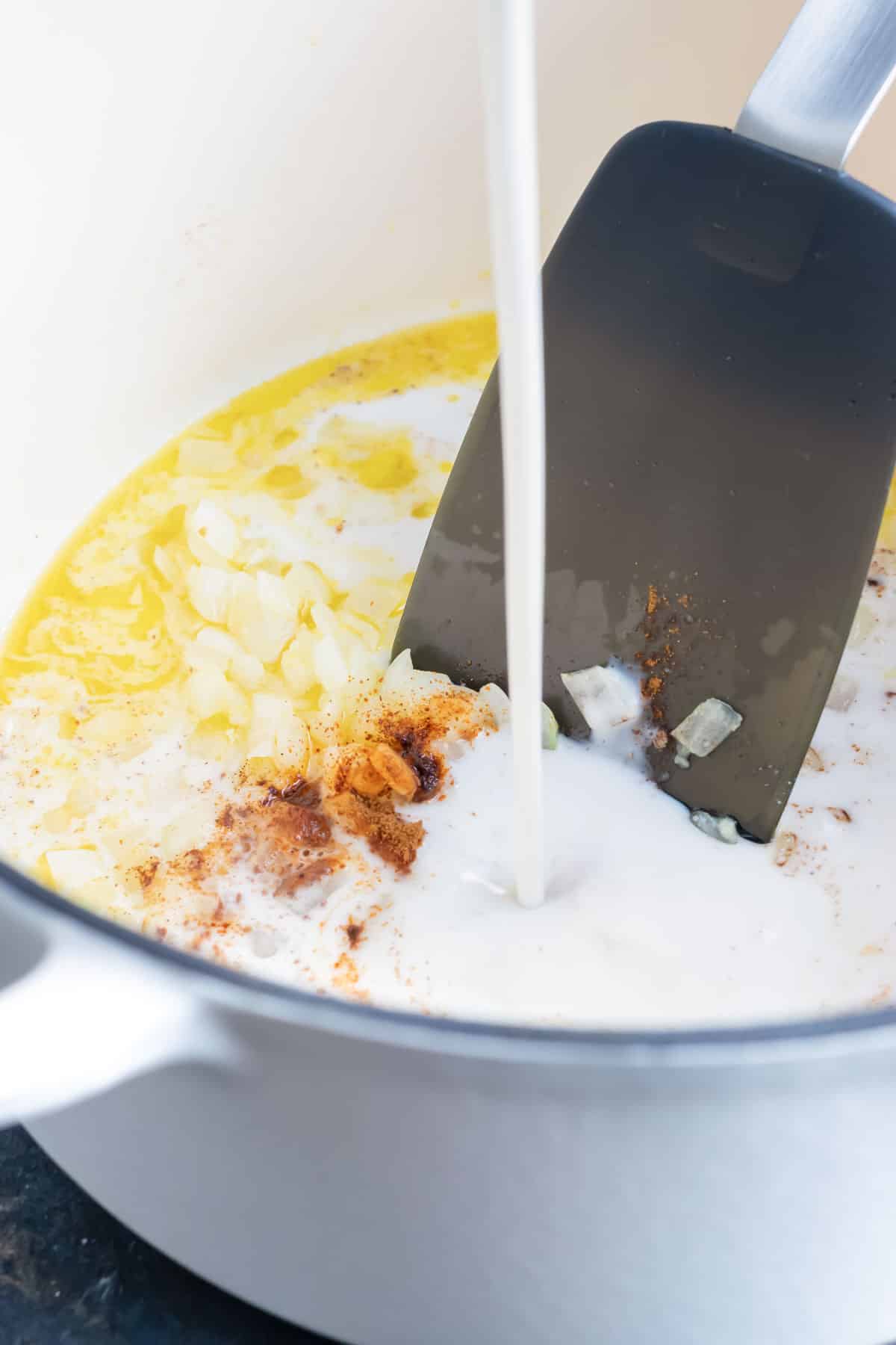 Coconut milk being poured into a Dutch oven to show how to make butternut squash soup.