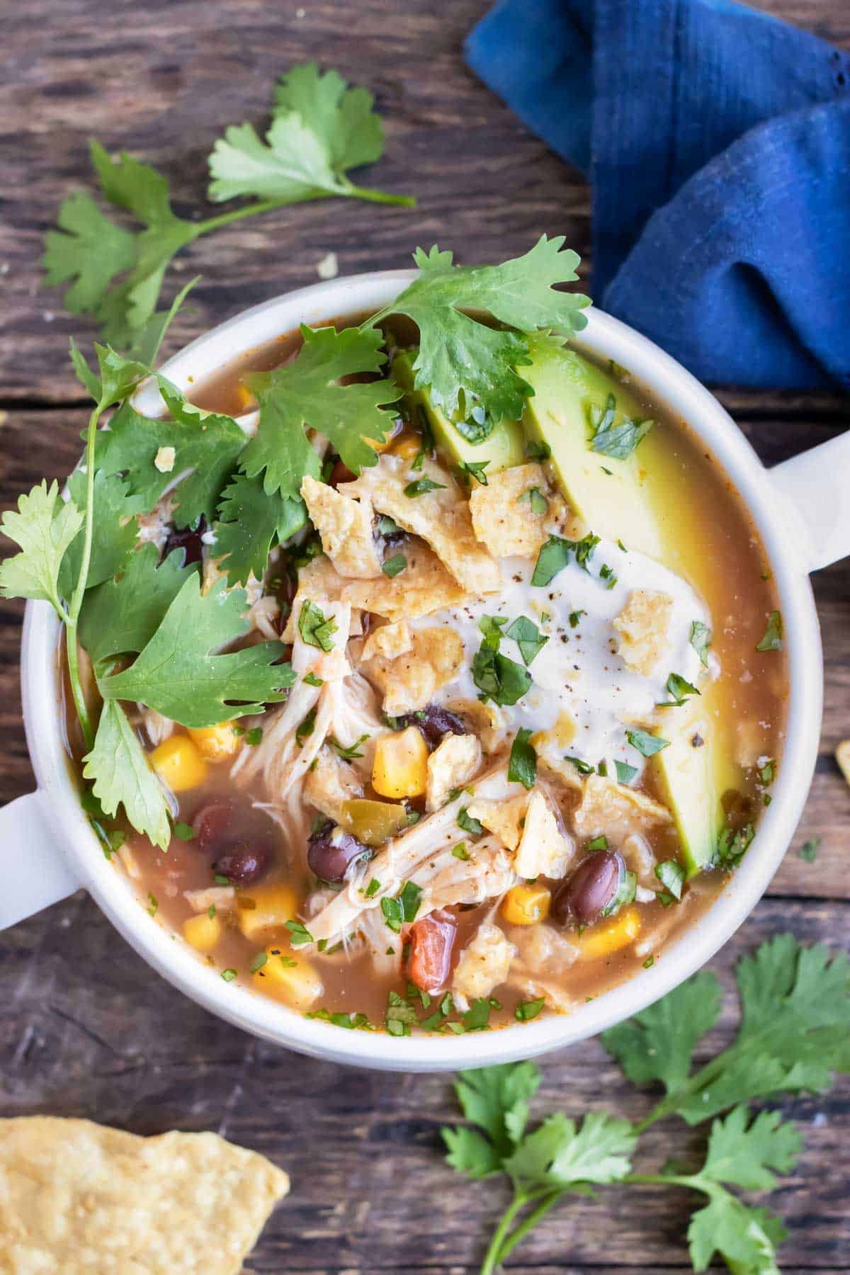 Crock-Pot chicken tortilla soup with fresh cilantro, sliced avocados, and sour cream on top.