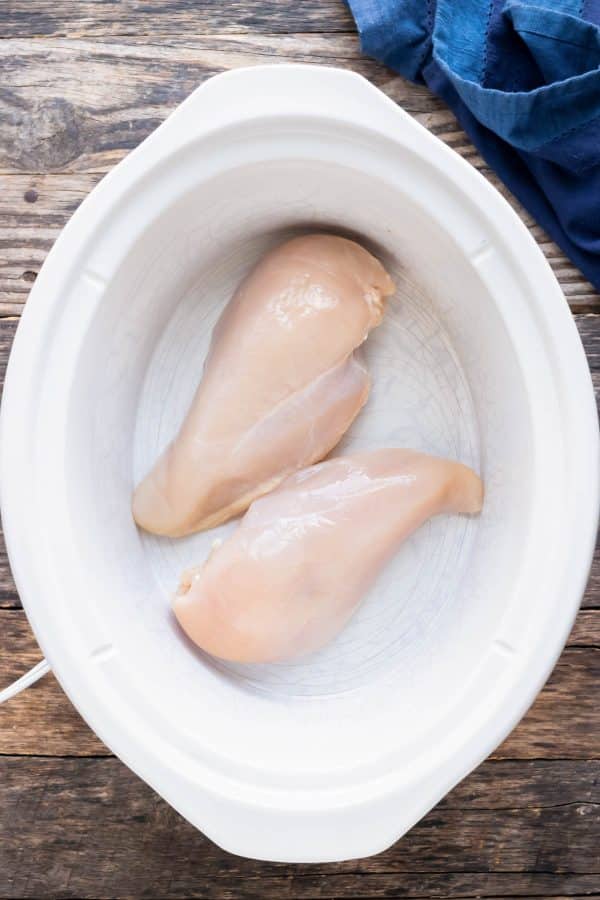Chicken breasts are placed in a crockpot.