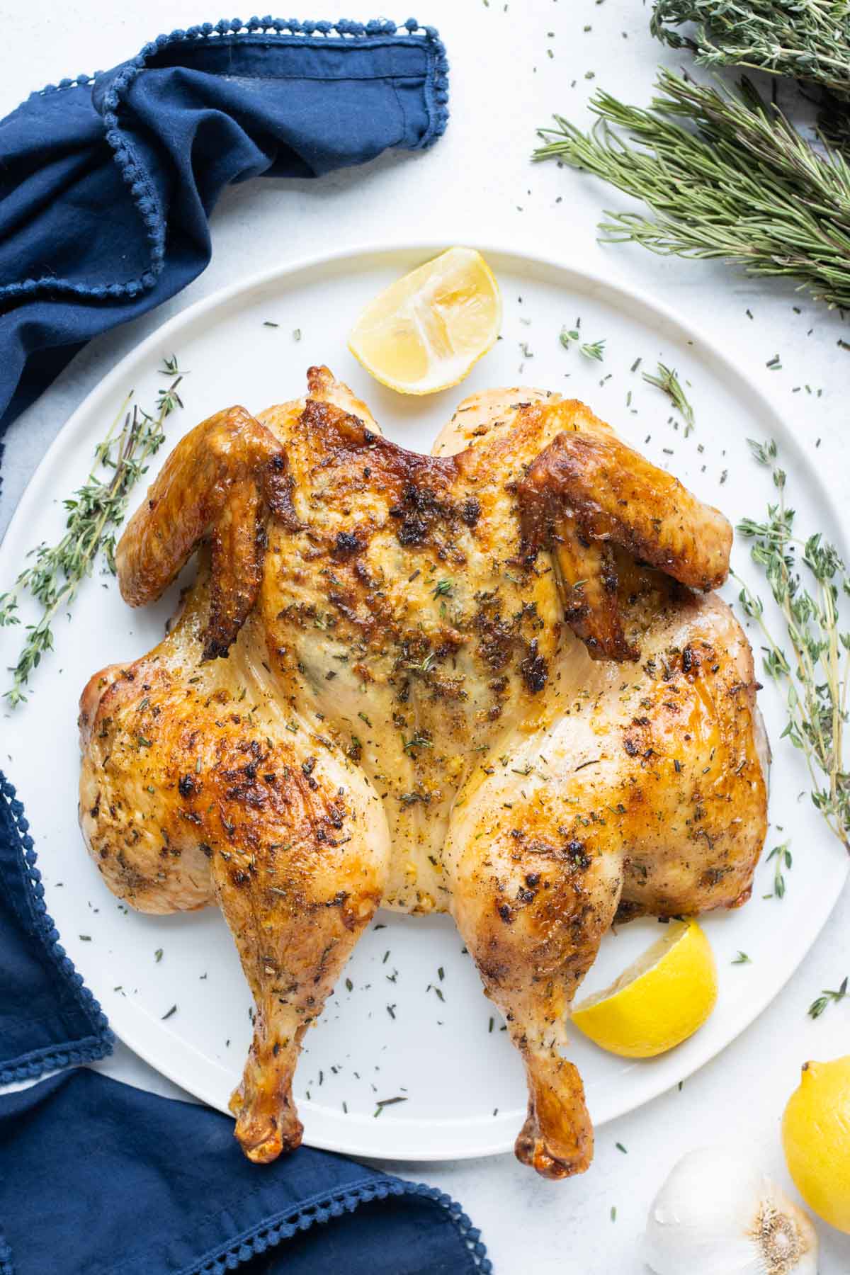A seasoned and baked chicken is on a serving dish.