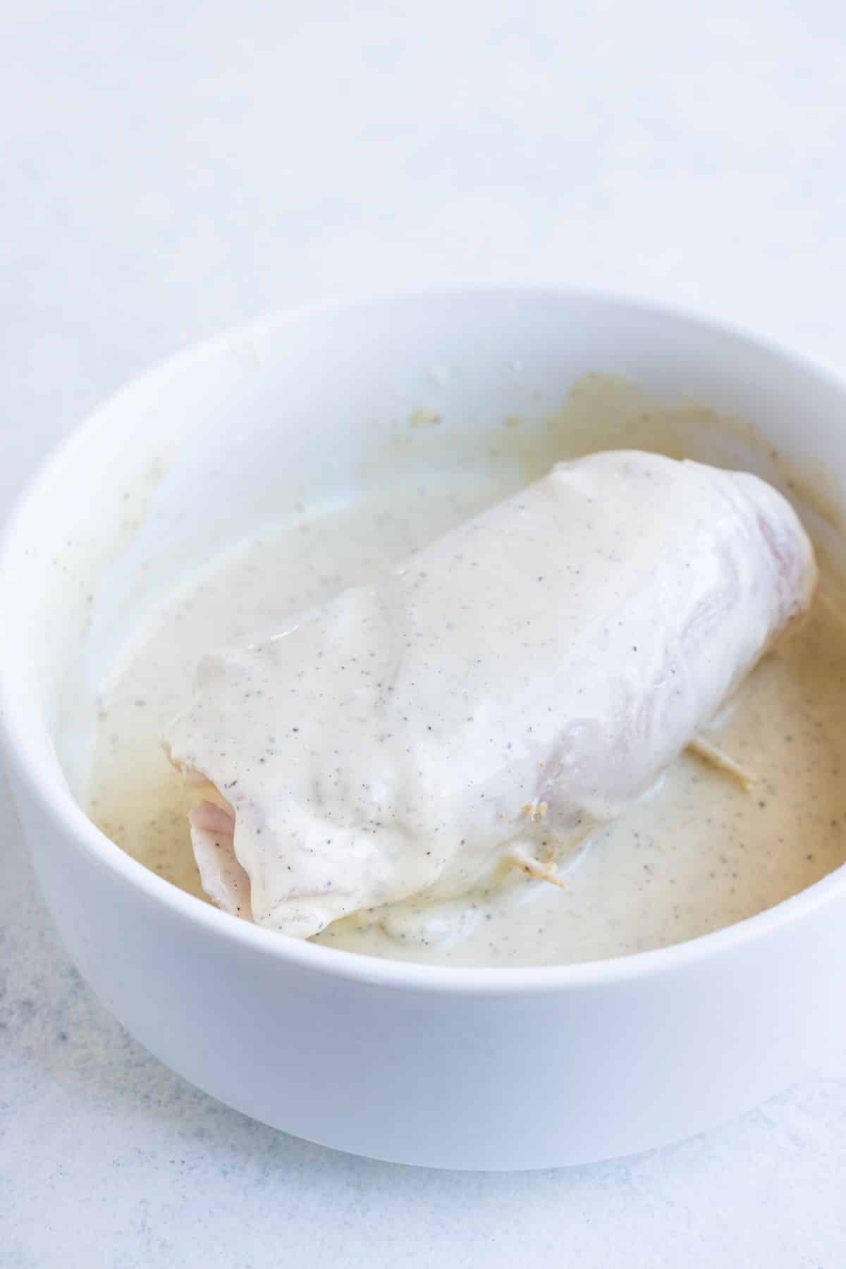 Chicken rolled with ham and cheese is dipped in a mayo mixture.