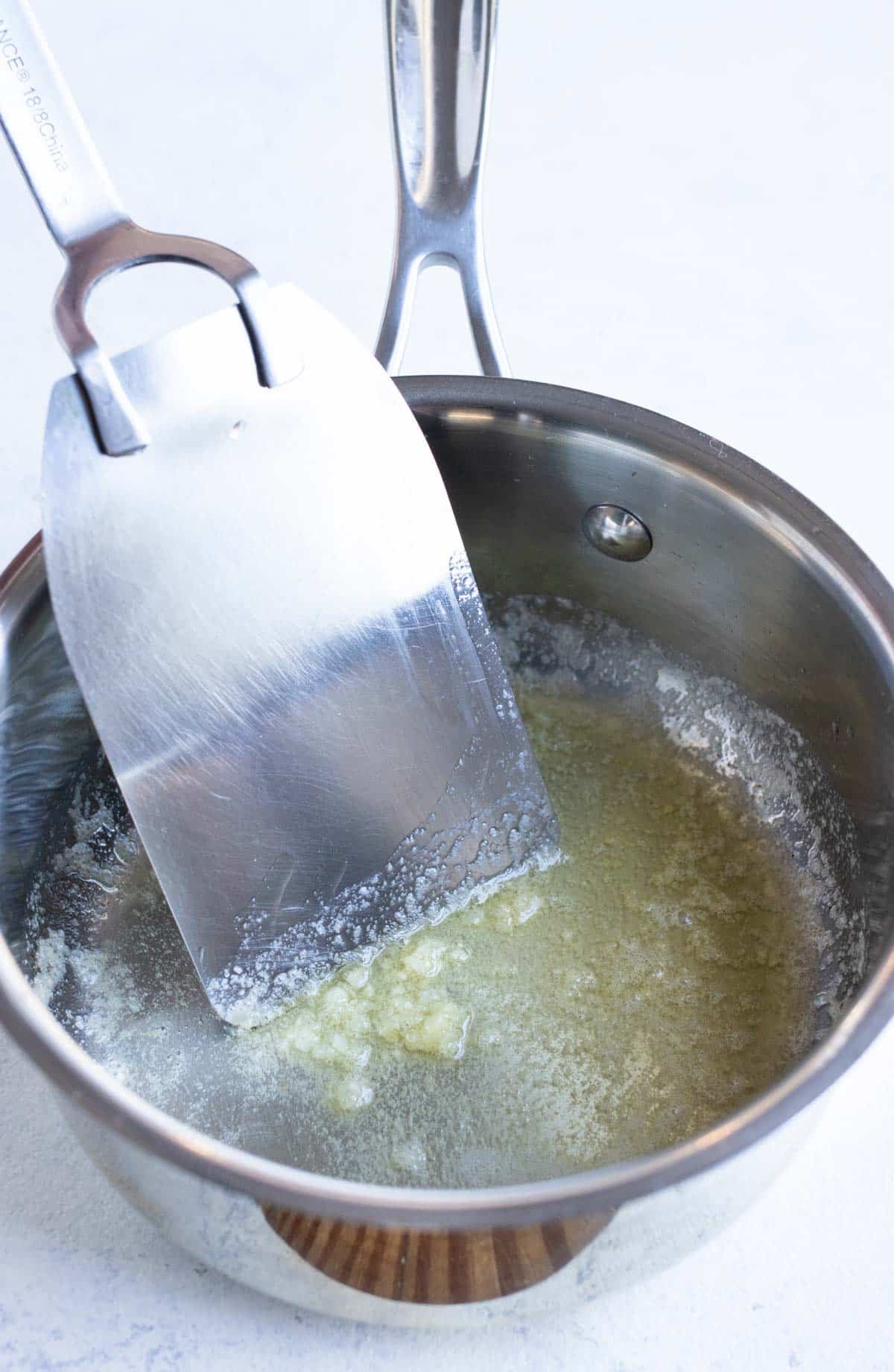 Butter and garlic are cooked together in a saucepan.