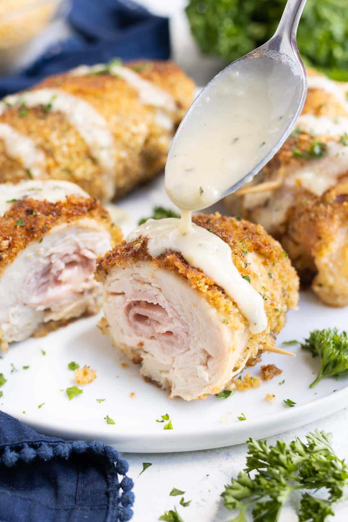 Chicken Cordon Bleu has ham and cheese in the middle and is drizzled with a creamy sauce.