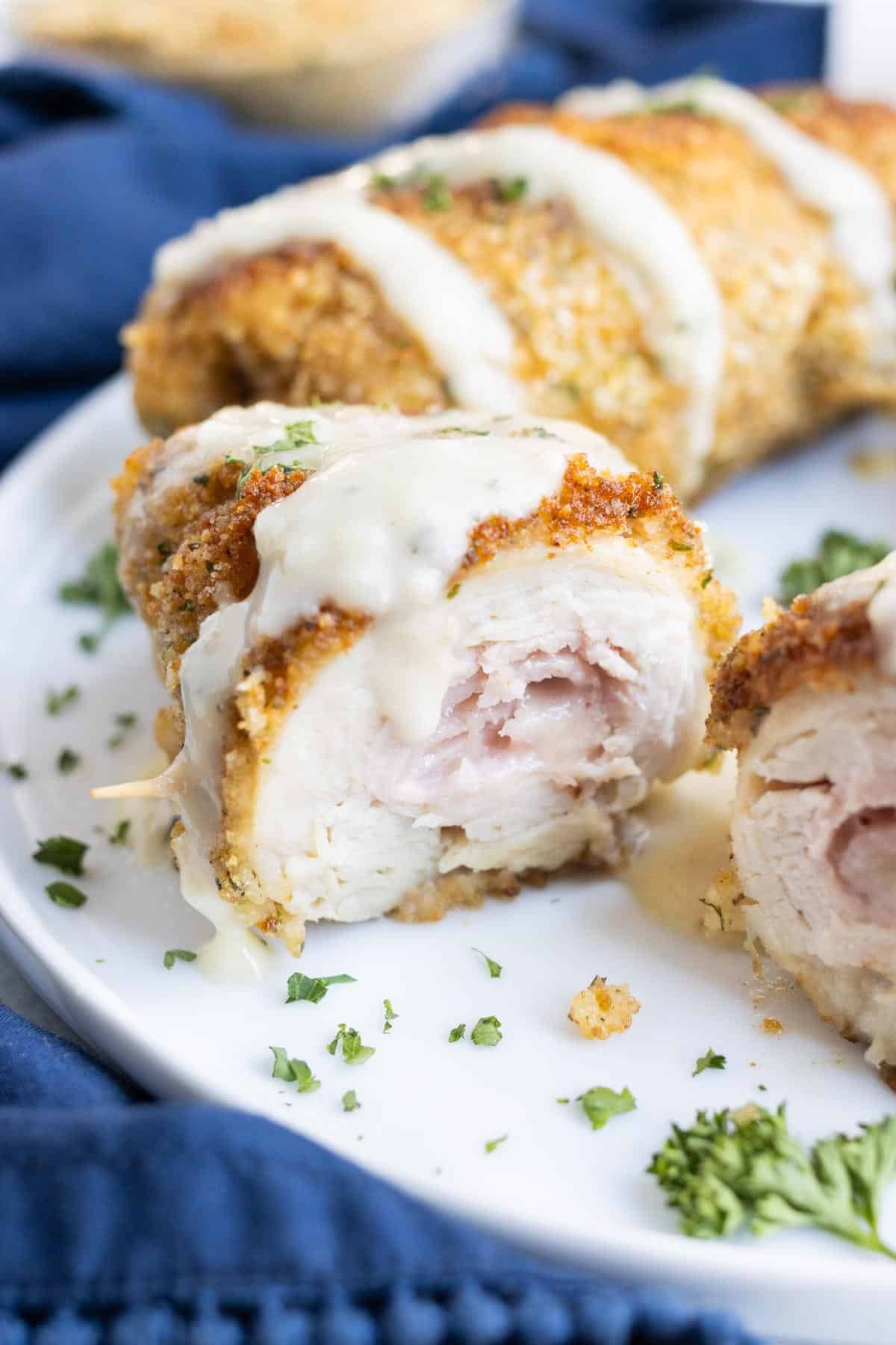 Chicken Cordon Bleu RECIPE cut opened and topped with sauce.