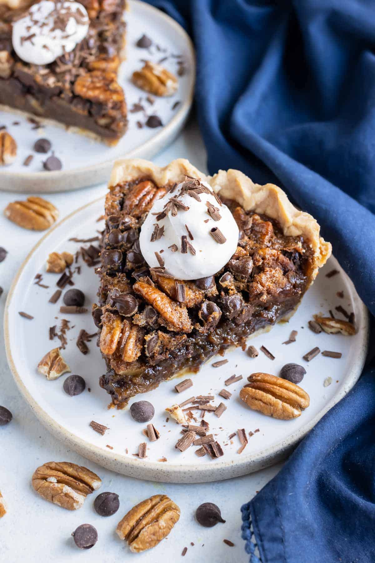 A dollop of whipped cream is put on a slice of pecan pie.