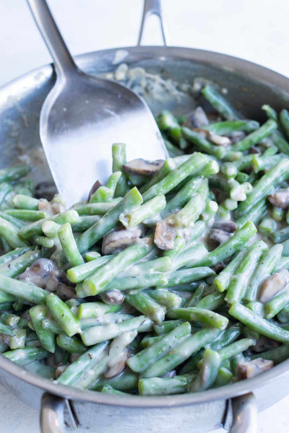 Green beans are added to a skillet with cream of mushroom soup.