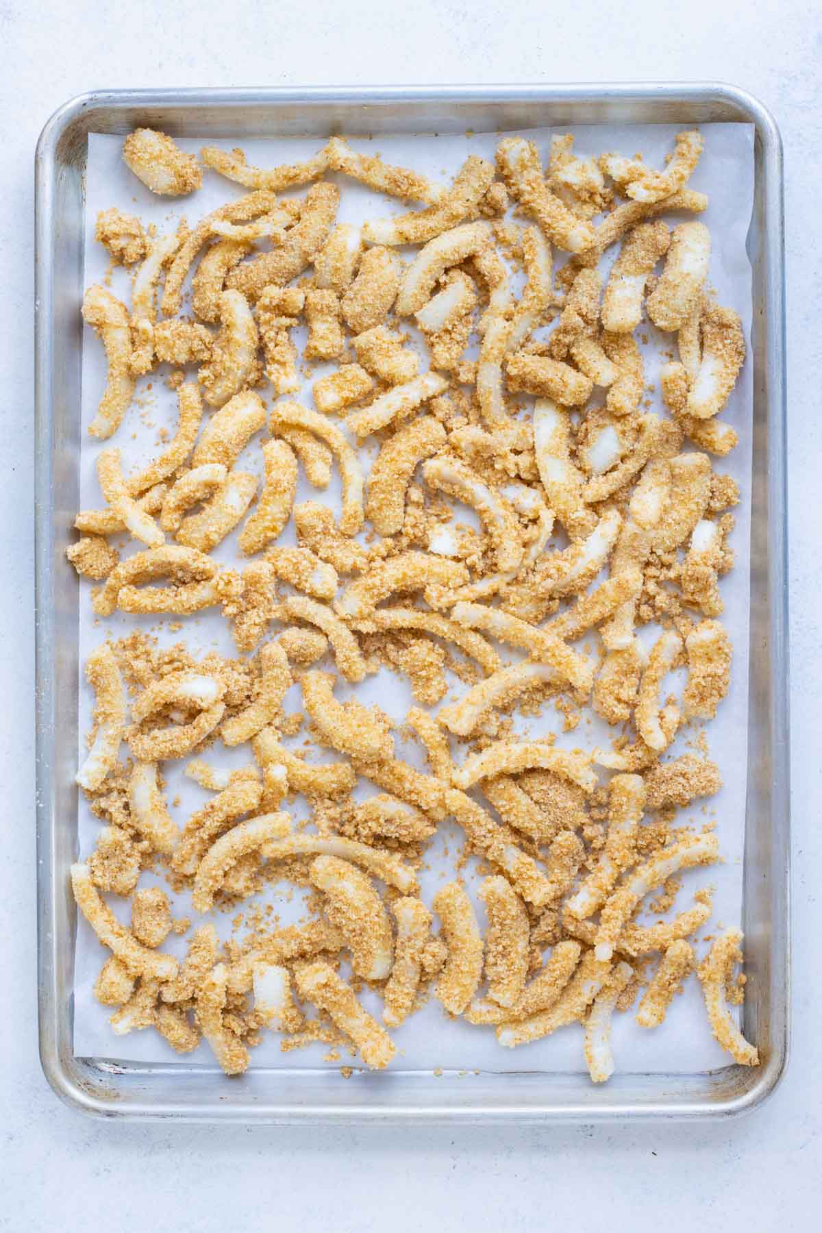 A tray of uncooked fried onions ready to bake.